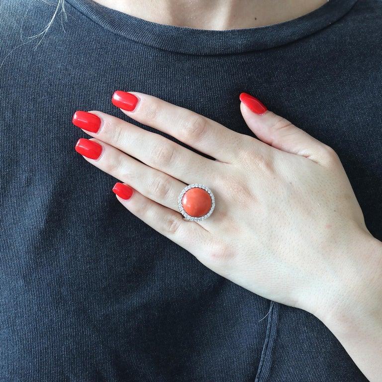 A colorful creation of natural beauty. Featuring a cabochon cut reddish-orange coral elegantly surrounded by a halo of near colorless diamonds. Crafted in 18k white gold. Ring size 7 and comes with complimentary sizing if needed. 