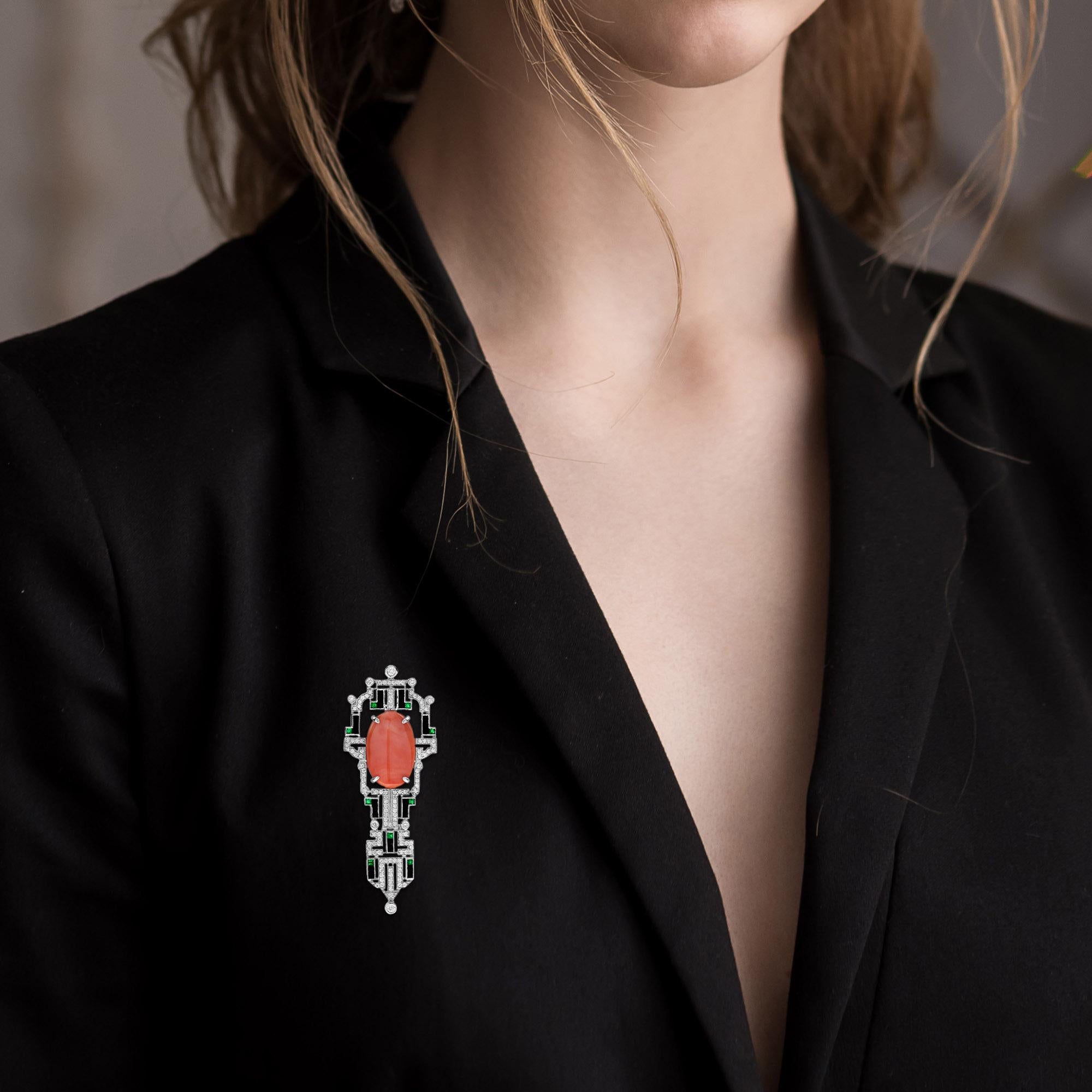 This gorgeous piece is set in 14k white gold with a Art Deco geometric style frame featuring a beautiful vivid orange 6.32 carat coral accented by 126 diamonds, onyxes, and emeralds. The clasp has a safety latch for added security. A perfect