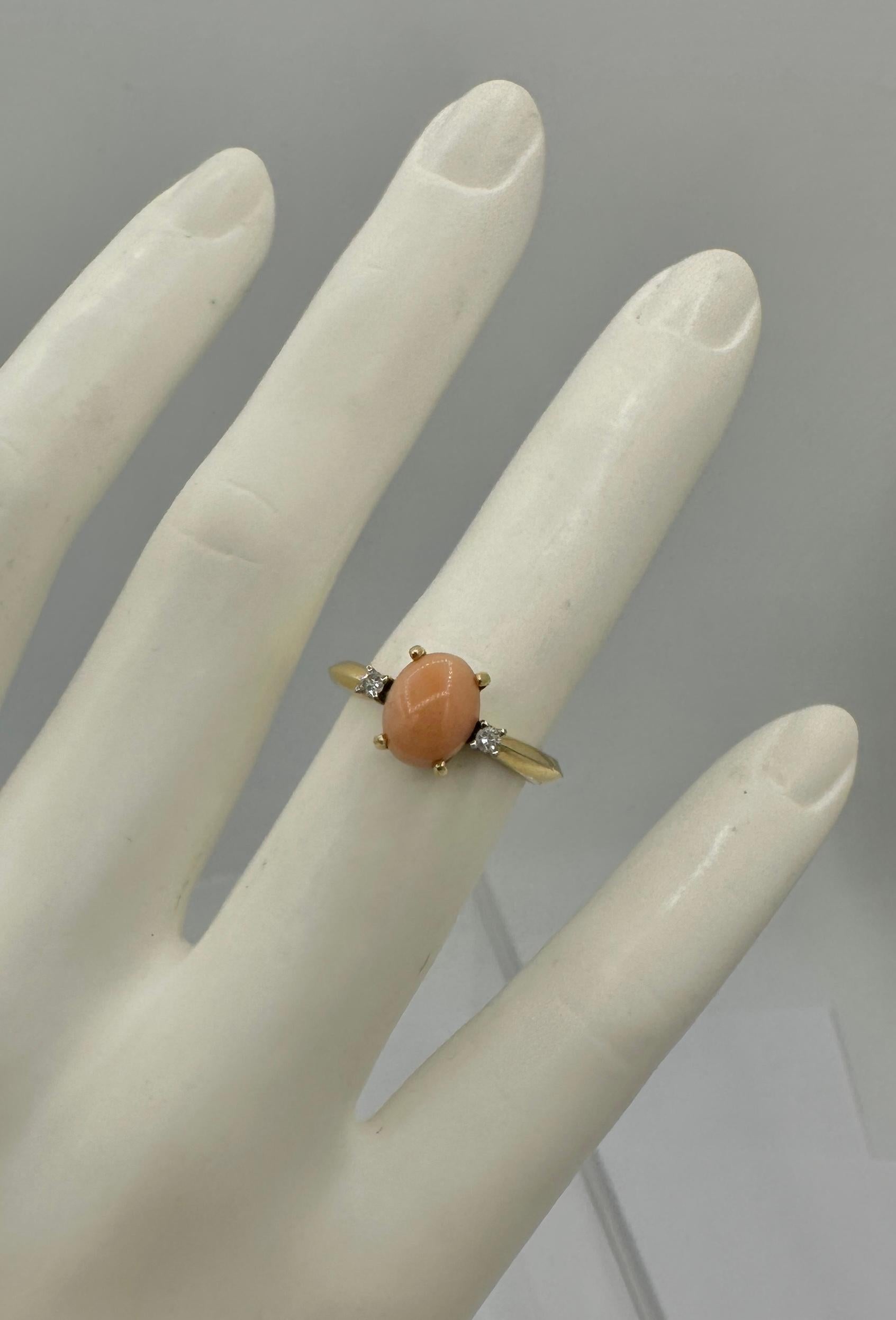 This is a wonderful Salmon Coral Diamond Ring in 14 Karat Gold.  The ring is a classic Art Deco design with its wonderful colors and style.  The ring features a natural oval Salmon Coral cabochon of 9mm in length.  On either side of the coral are