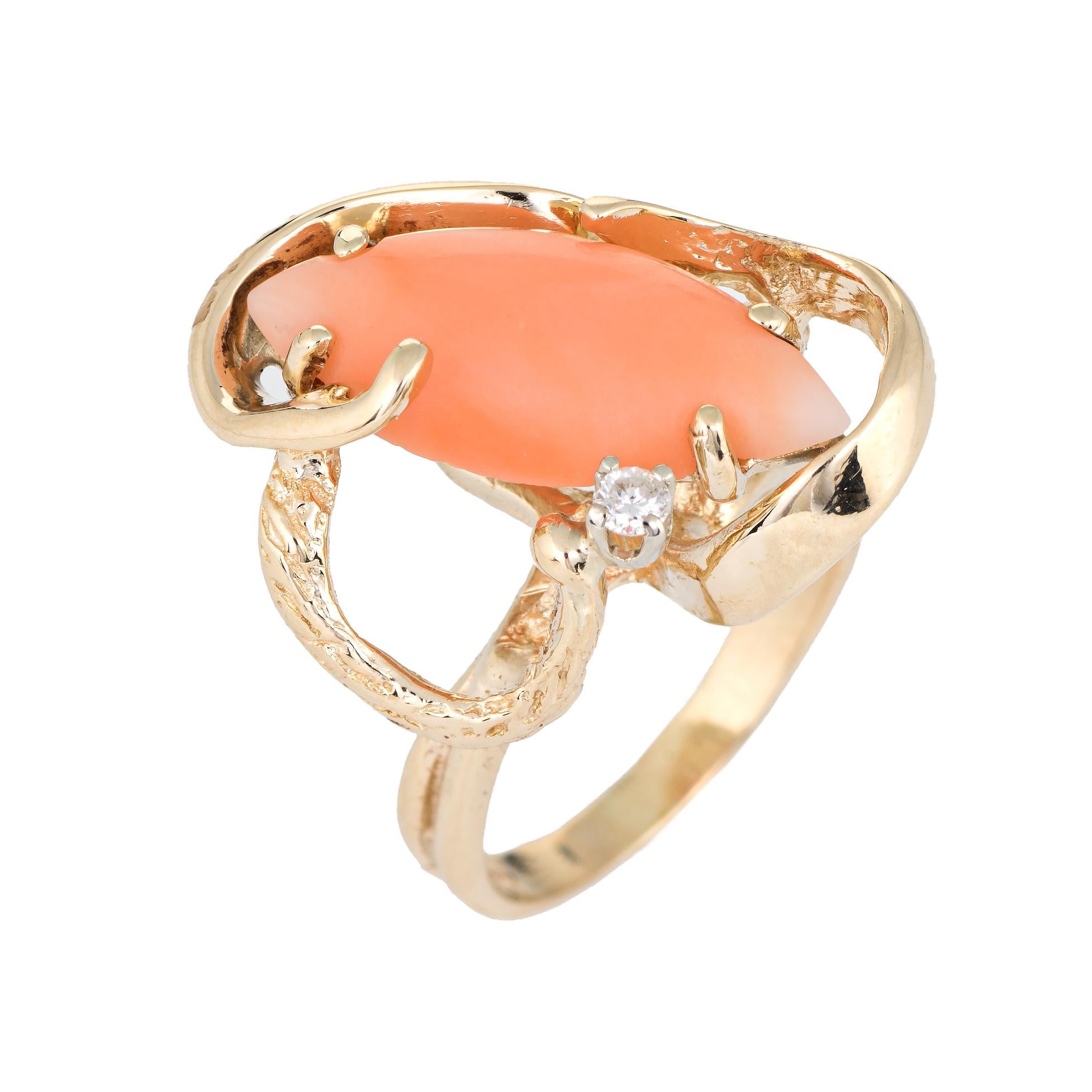 Stylish vintage coral & diamond ring (circa 1960s to 1970s) crafted in 14 karat yellow gold. 

Cabochon cut marquise shaped coral measures 18mm x 8mm (estimated at 4.50 carats), accented with one estimated 0.02 carat diamond (estimated at H-I color