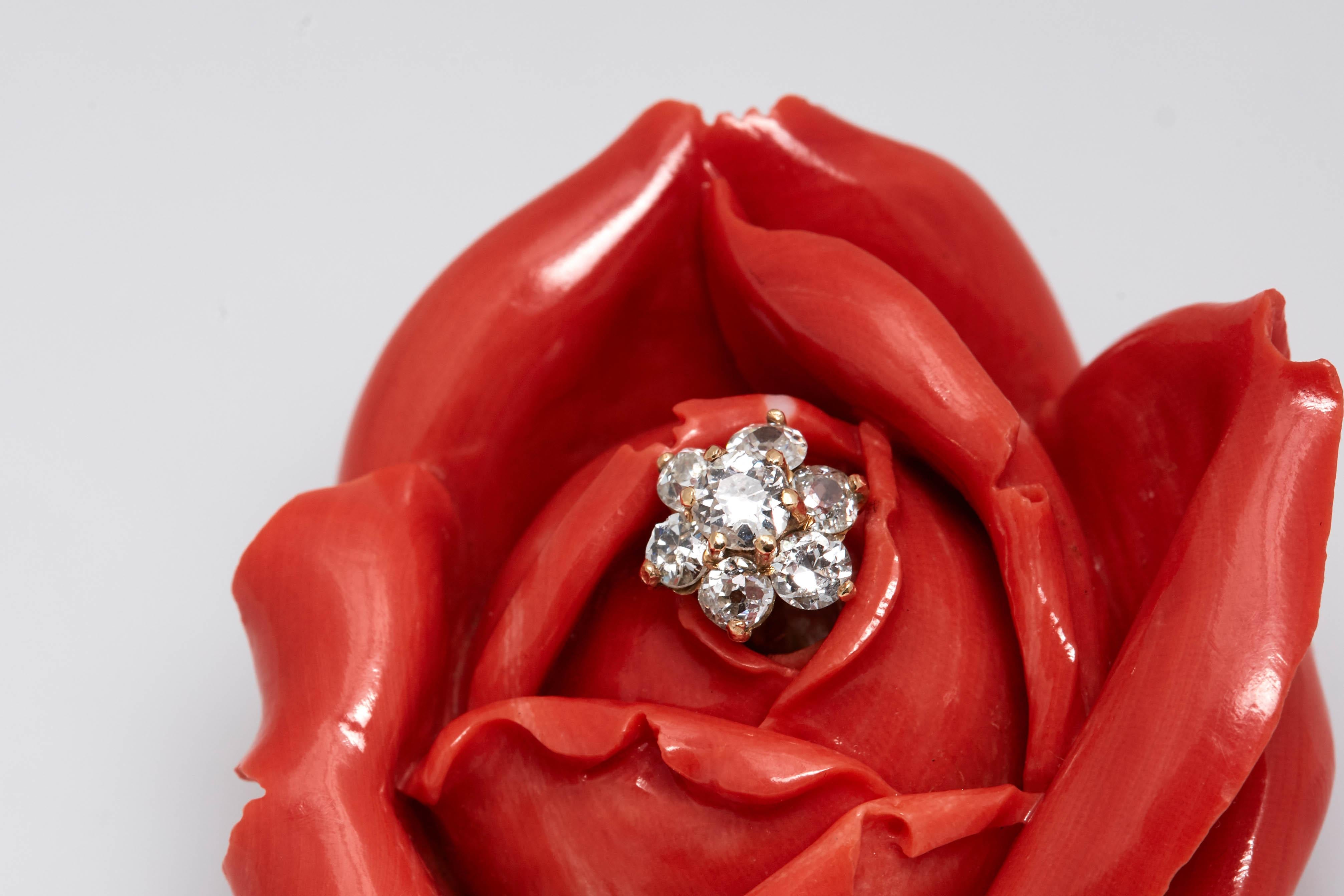 A Platinum, Gold, and Carved Coral and Diamond Rose Brooch. Made in Italy, circa 1965
Topped by a carved coral rose approximately 52.0 x 45.0 mm., centering a cluster of 7 old-mine and old European-cut diamonds approximately .85 ct., supported by a