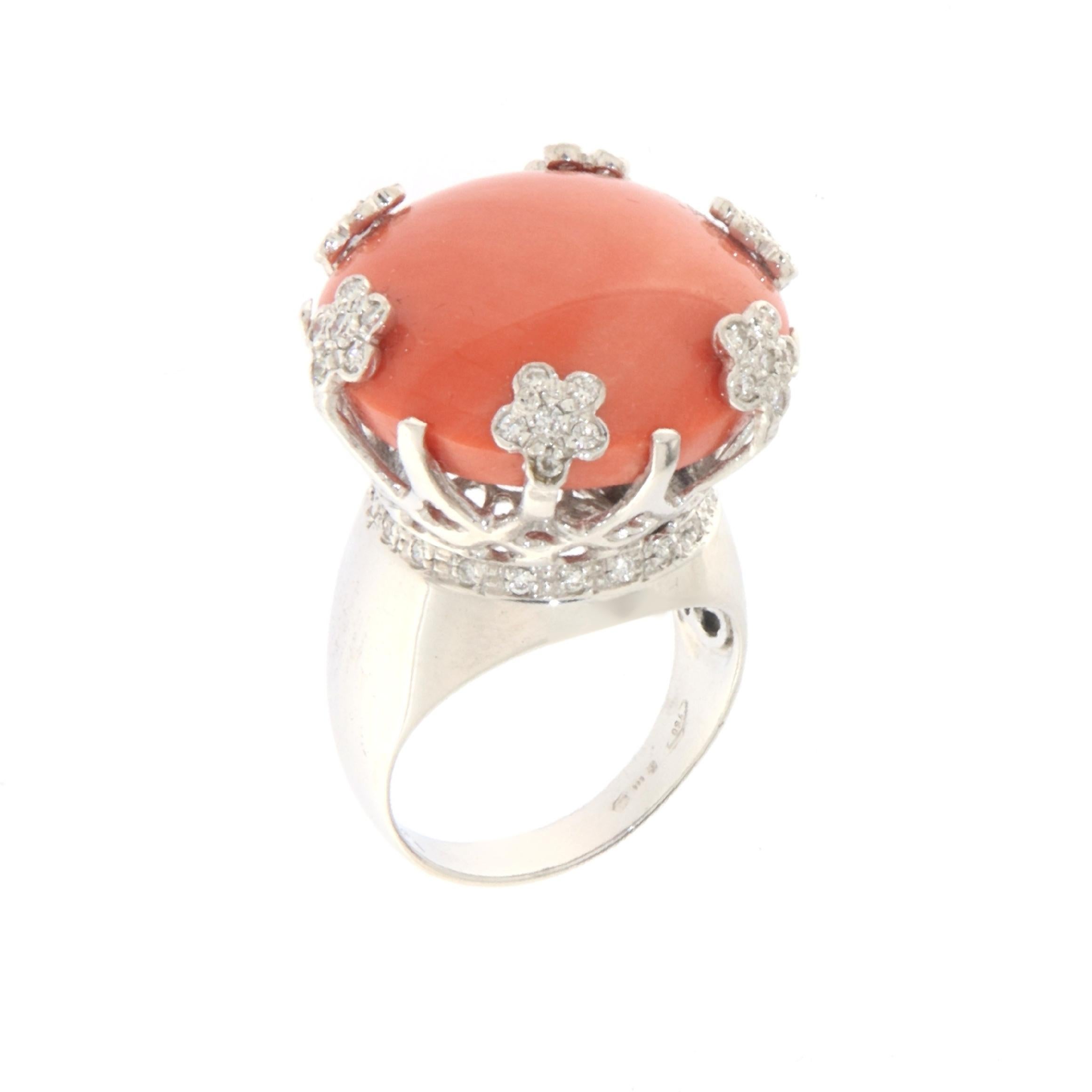 This elegant ring in 18-karat white gold is a sublime example of craftsmanship and refined material selection. At its center, lies a natural coral button, whose delicate and sophisticated shade stands apart from the usual fiery red, evoking the