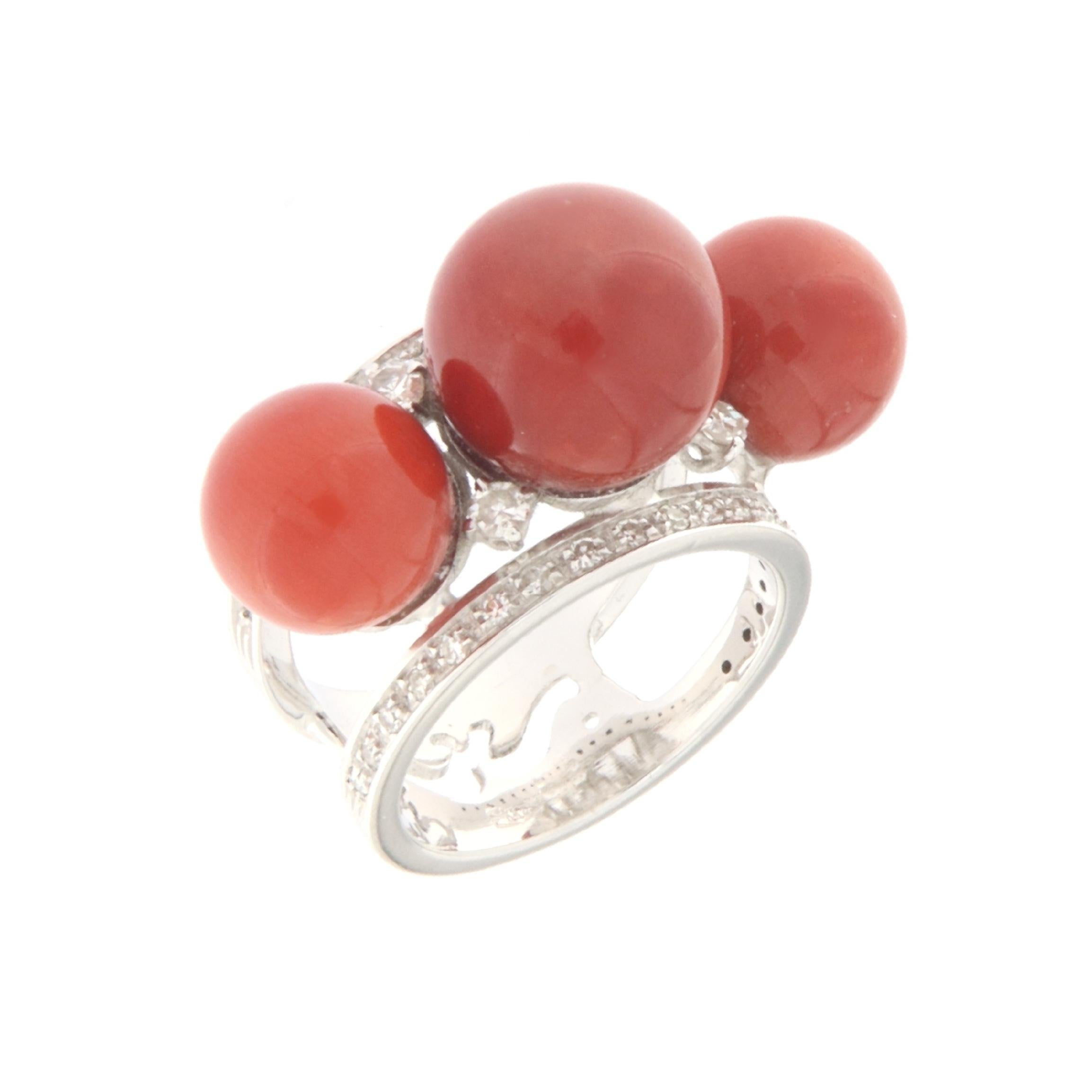 This refined band ring in 18-karat white gold is a true expression of elegance and style. Characterized by a contemporary design, the ring stands out for the presence of three spheres of natural red coral, balanced along the band. These gems,