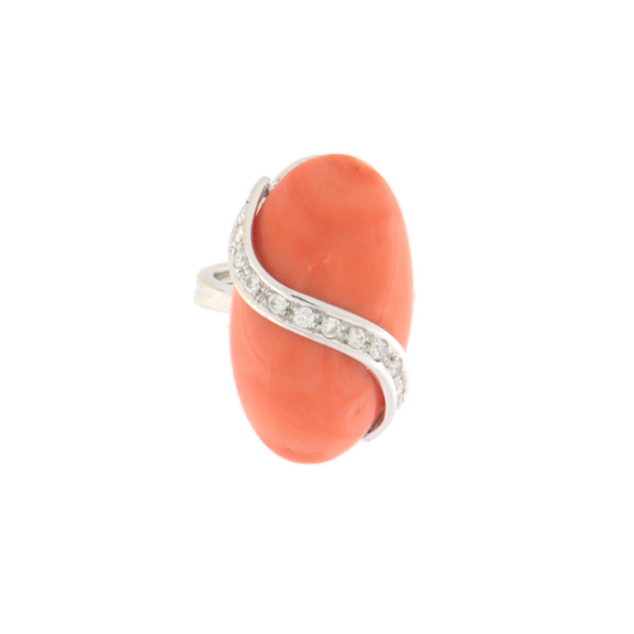 This magnificent 18-karat white gold ring is a true masterpiece of elegance and refinement, designed for those who appreciate distinctive and timeless jewelry. At the center of attention stands a stunning natural coral stone, featuring warm, intense