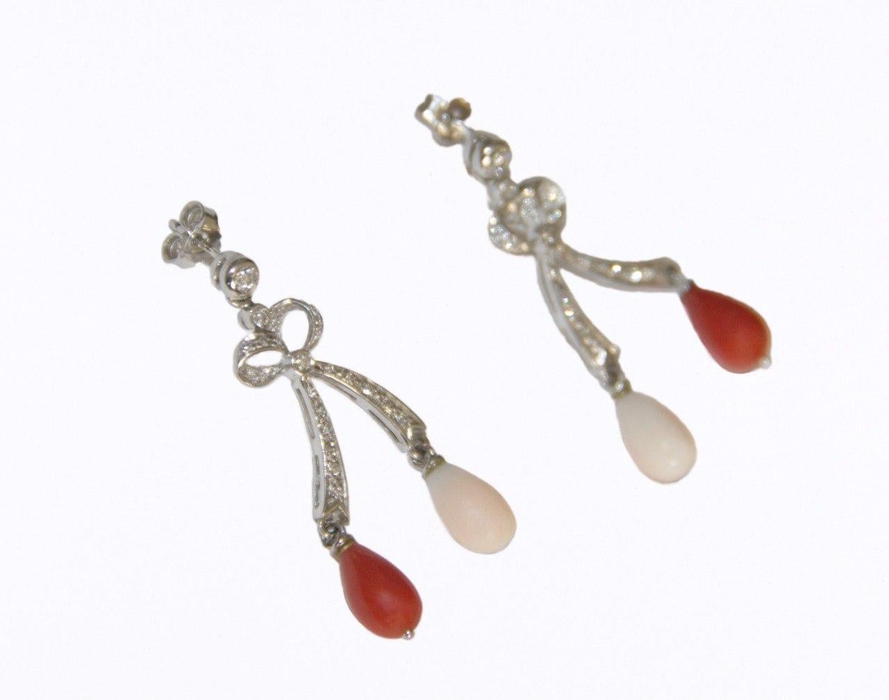A sophisticated blend of elegance and artistry, these 18-karat white gold earrings are the epitome of refined luxury. The design features two stunning coral drops—one in a vibrant red and the other in a soft pink—suspended delicately to create a