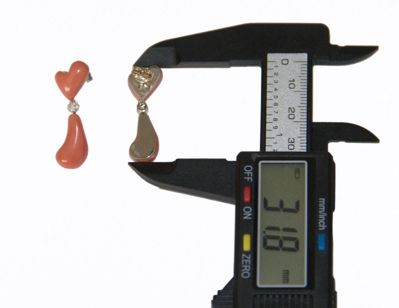 These elegant 18-karat white gold earrings are a charming expression of timeless beauty and artistic design. Each earring features a delicately carved coral heart at the top, complemented by a coral comma-shaped drop that adds movement and a unique