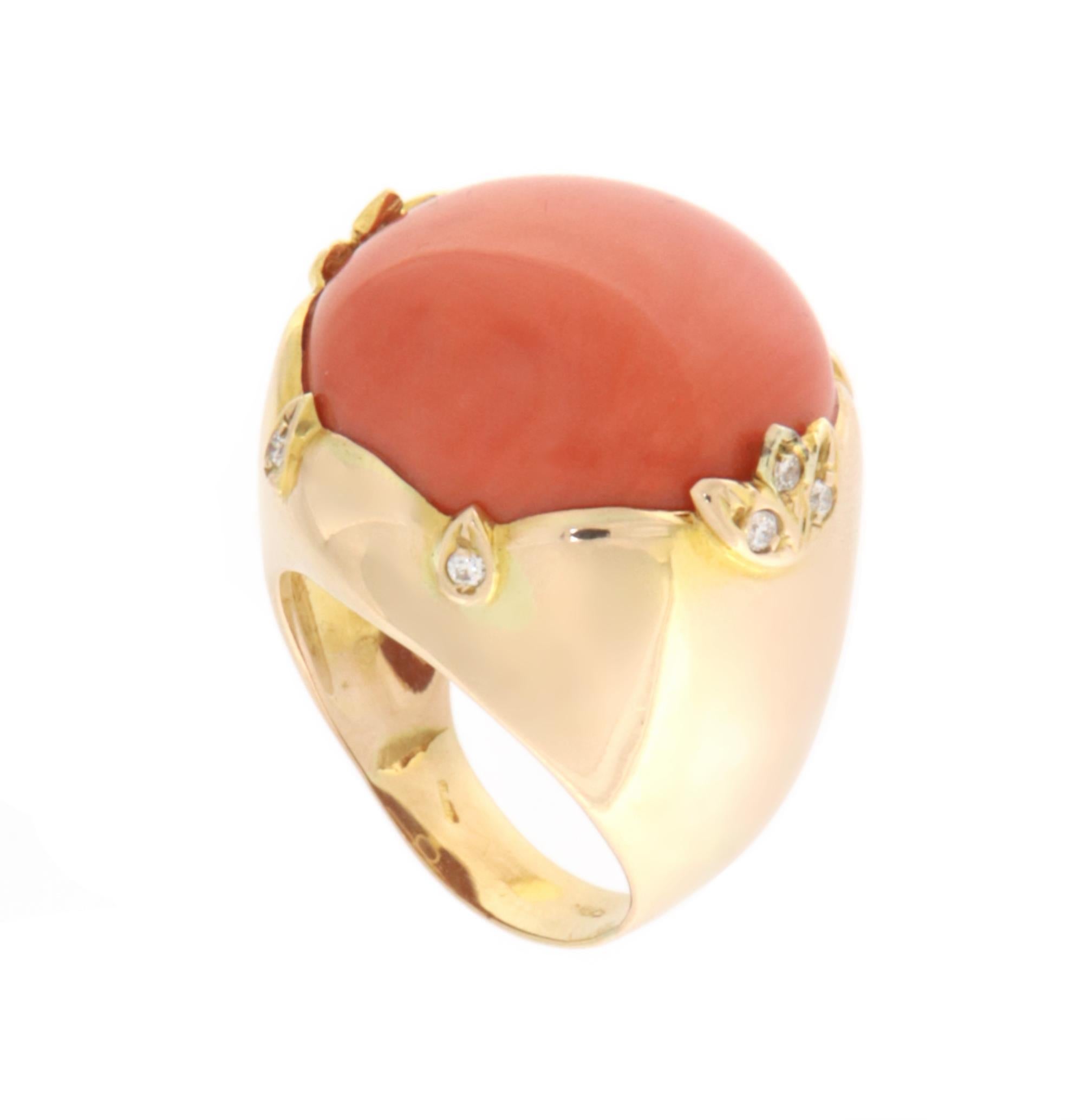 Elegant ring crafted in 18-karat yellow gold, featuring a unique and captivating design. At the center of the ring is a stunning natural coral, carefully selected for its intense color and full, harmonious shape. The warm and vibrant hue of the