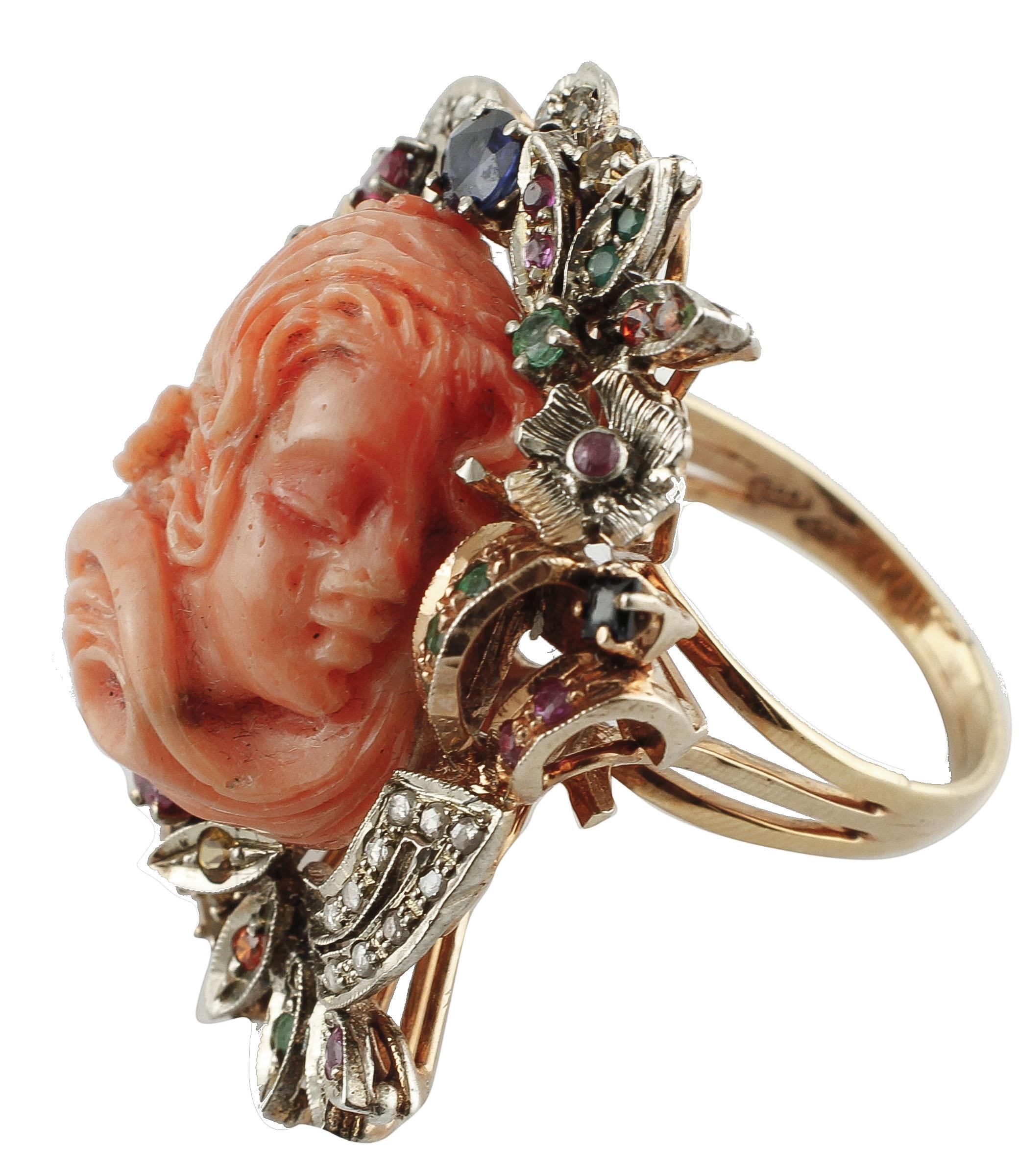 Marvelous ring in 9k rose gold and silver structure, mounted with a central finely carved elatius coral, surrounded by flowery details in rose gold and silver studded with diamonds, rubies, emeralds and multicolored sapphires.
This ring is totally