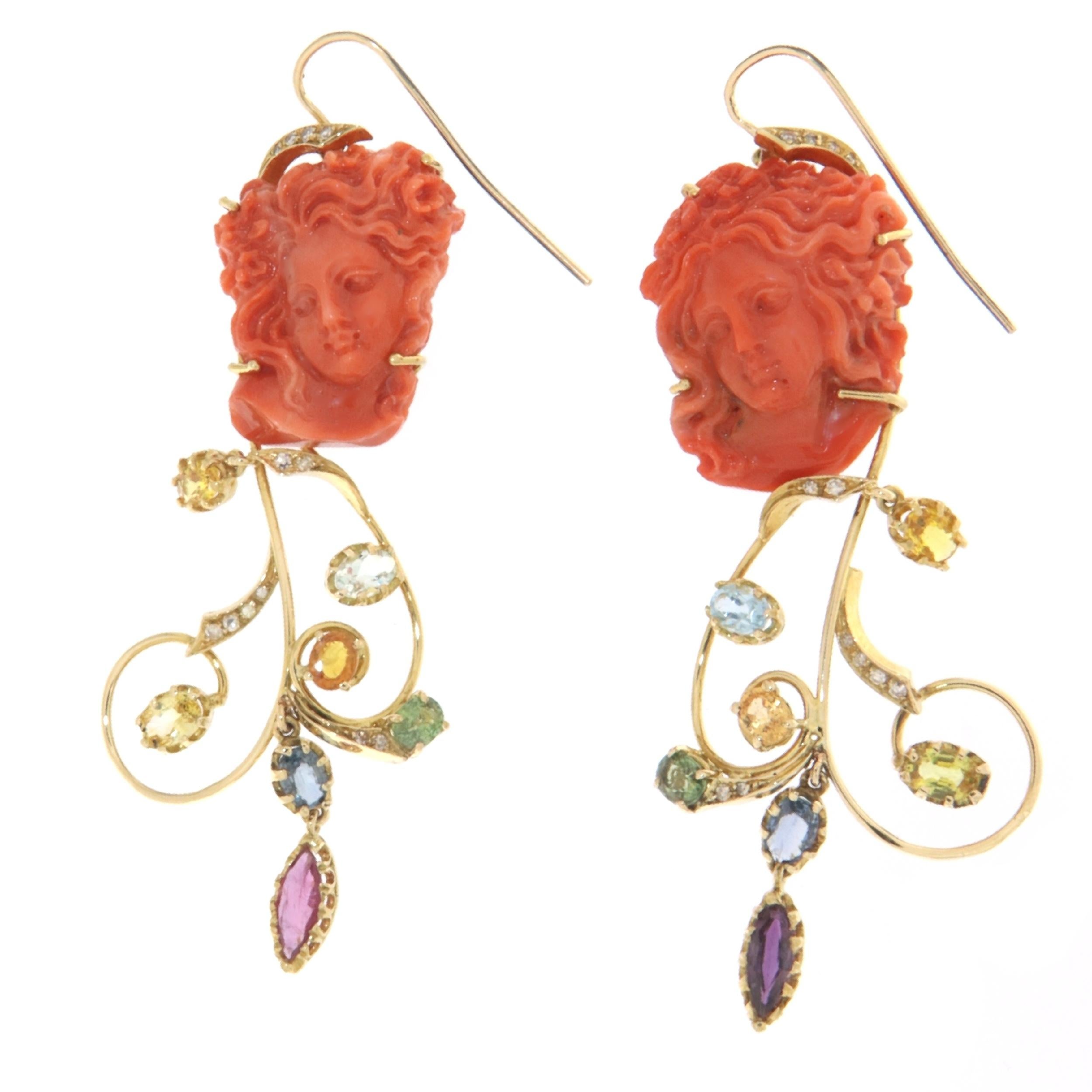 Spectacular Drop Earring made of 14K yellow gold, with an engraved coral woman face of a woman supporting a structure made up of gold ornaments and colored stones.

The textures of the colors and the surrounding flourishes outline the beauty of the