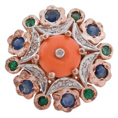 Anello con corallo, smeraldi, diamanti, zaffiri, oro rosa e argento.