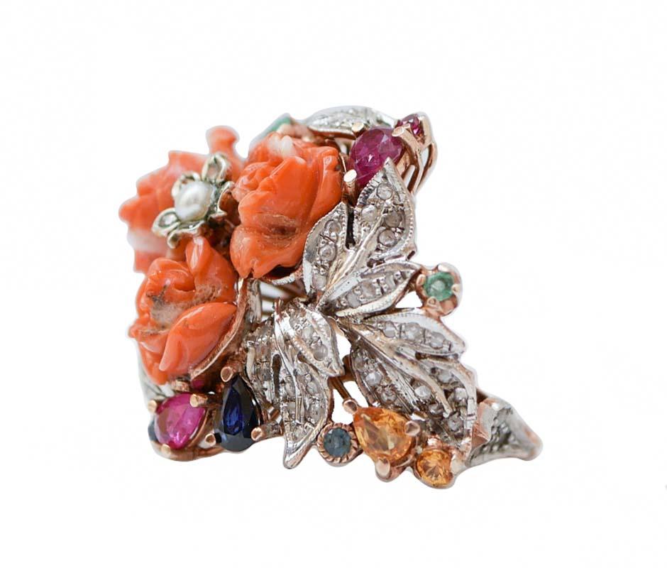 Fantastic ring in 9 kt rose gold and silver structure mounted  with three flowers of coral in the central part with a little flower of diamonds surrounded by diamonds, emeralds, rubies and sapphires.
This ring was totally handmade by Italian master