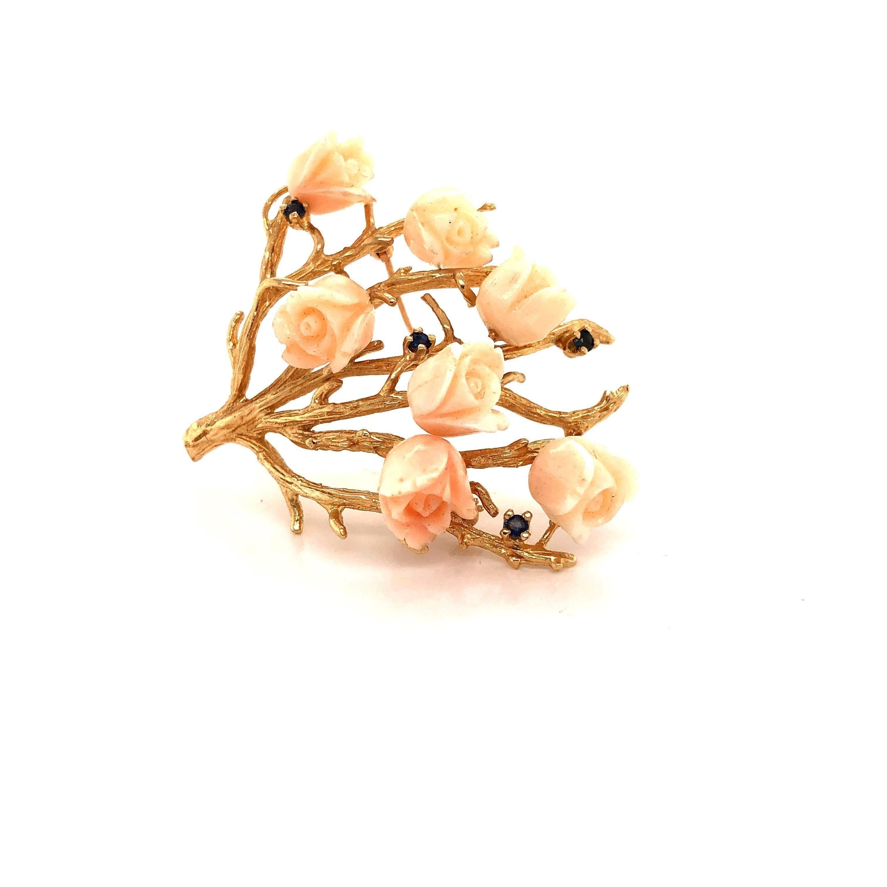 Exquisite detail shown on this coral brooch. The details are endless as this brooch is crafted in 14k yellow gold. Seven angels breath coral rose's are set along this brooch giving it an amazing look. Set along the flower petals are sapphires and