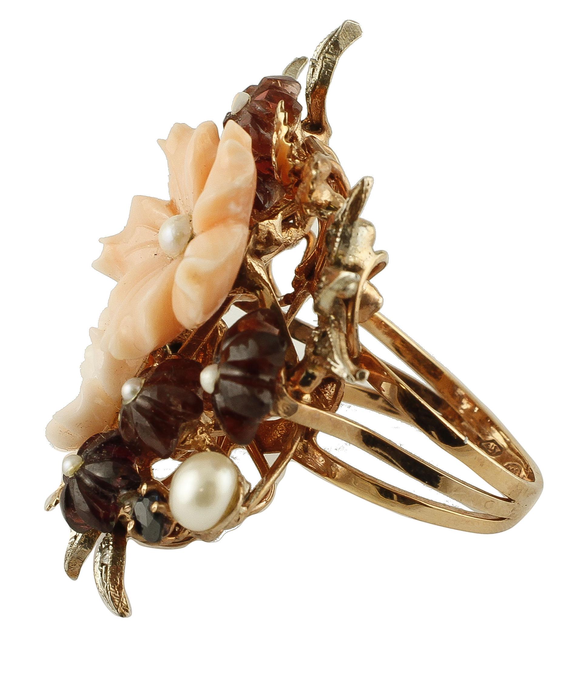 Beautiful flowery ring in 9k rose gold and silver  structure. The ring features 2 secundum coral flowers with central little pearls and many little flowers all around made of garnets pearls. The ring is also enriched by flowery decoration in rose