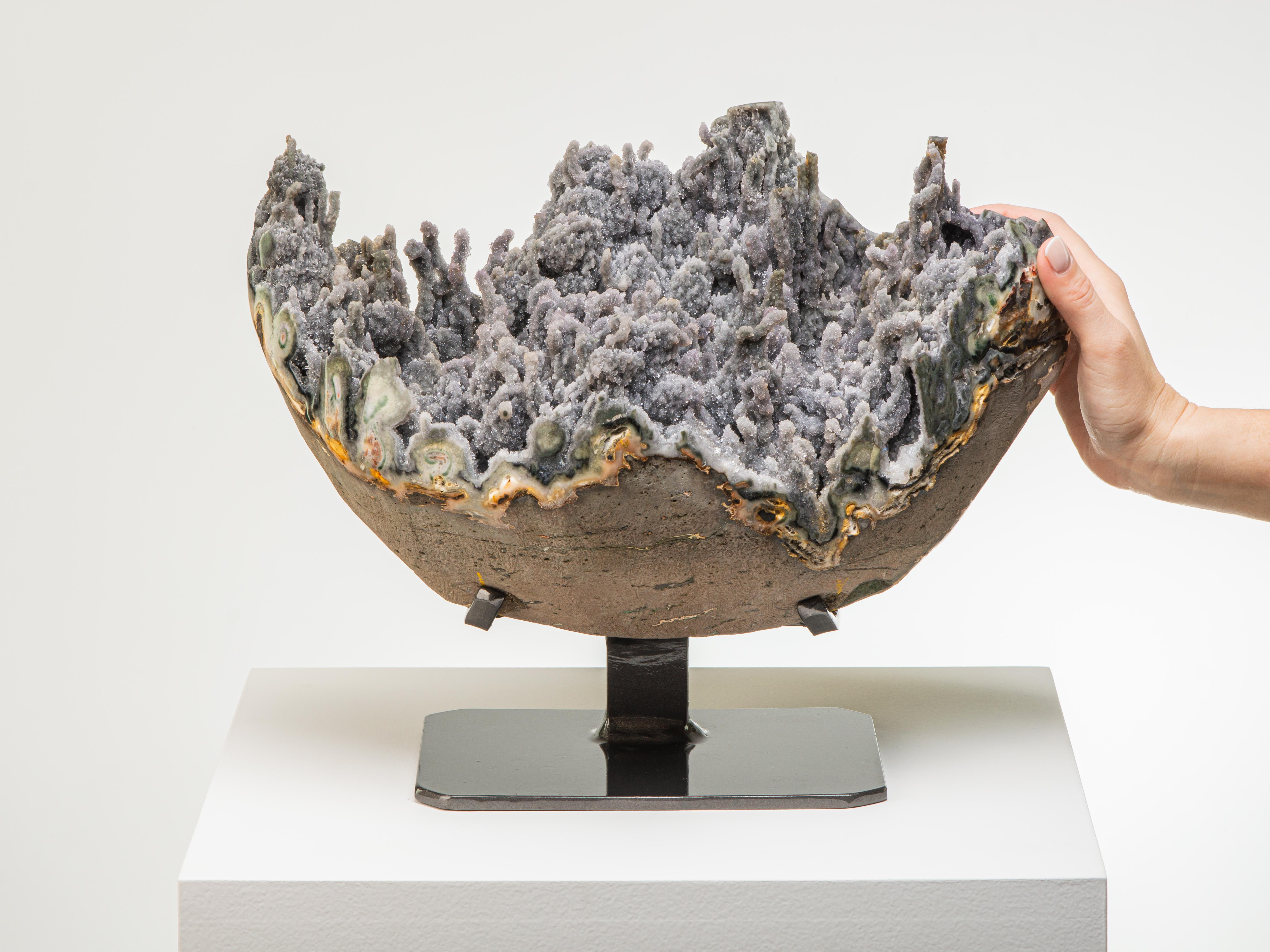 Beautiful green-grey coral-like stalactites emerge from the interior lining of this
round geode. The borders polished to reveal the celdonite shell with the exterior
basalt still visible.

This piece was legally and ethically sourced directly in