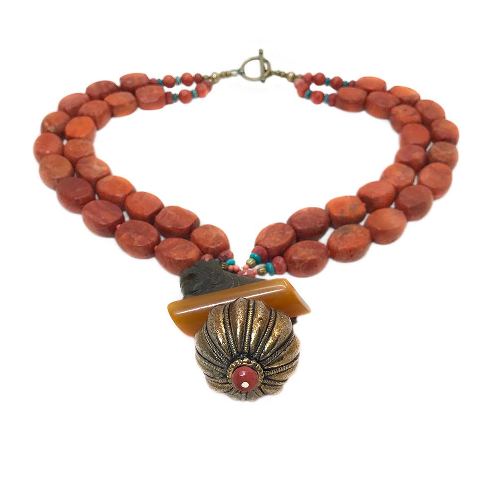 This is a coral necklace with lion pendant. Nouveau Boutique created this double strand necklace with sponge coral nuggets, facet coral beads and a brass toggle clasp. It features a large pendant that was wired with a carved brown stone lion seated