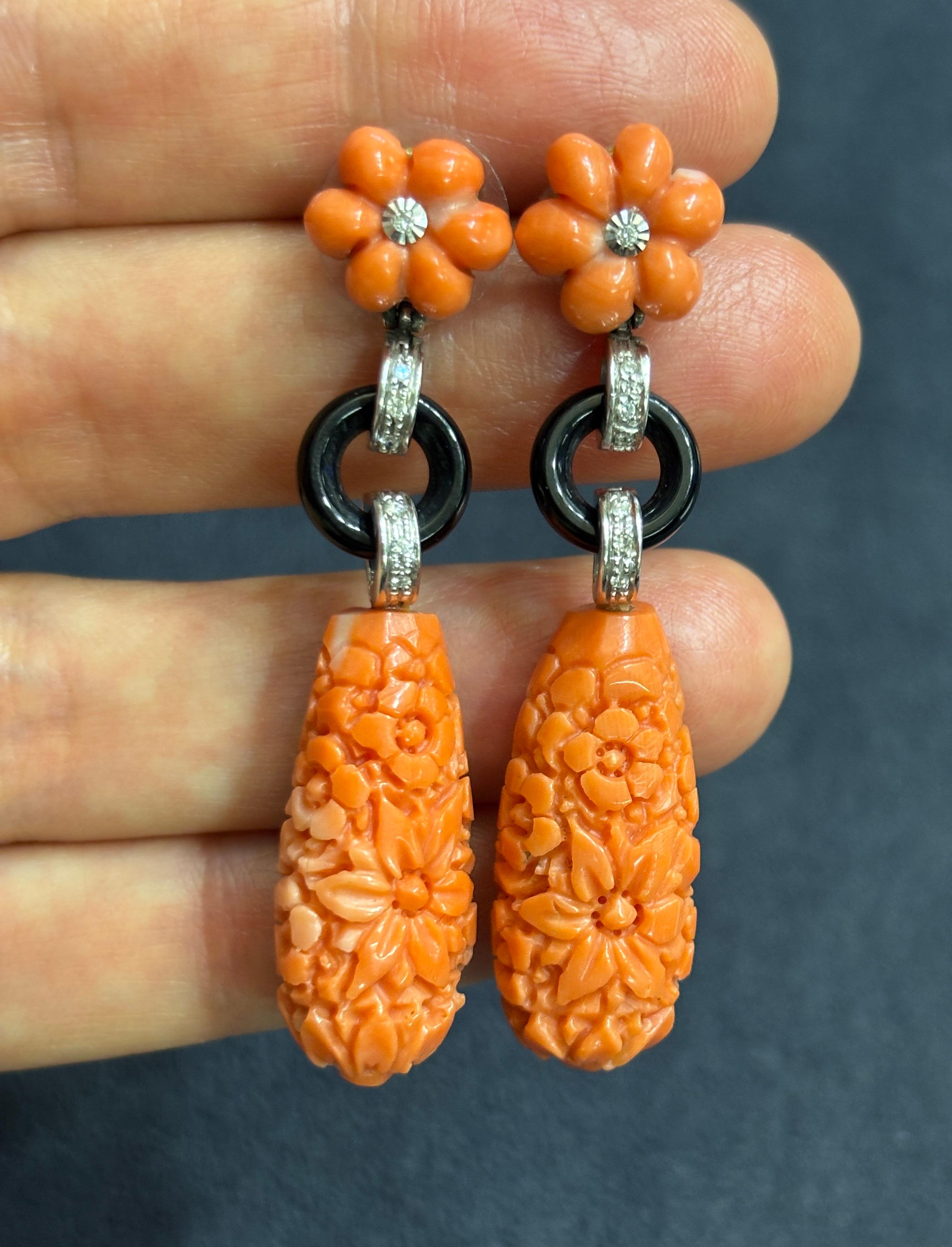 The floral design of these stylish 1970's dangly earrings have been carved into the coral. They are accentuated by the rings of onyx and 7 small diamonds on each earring.