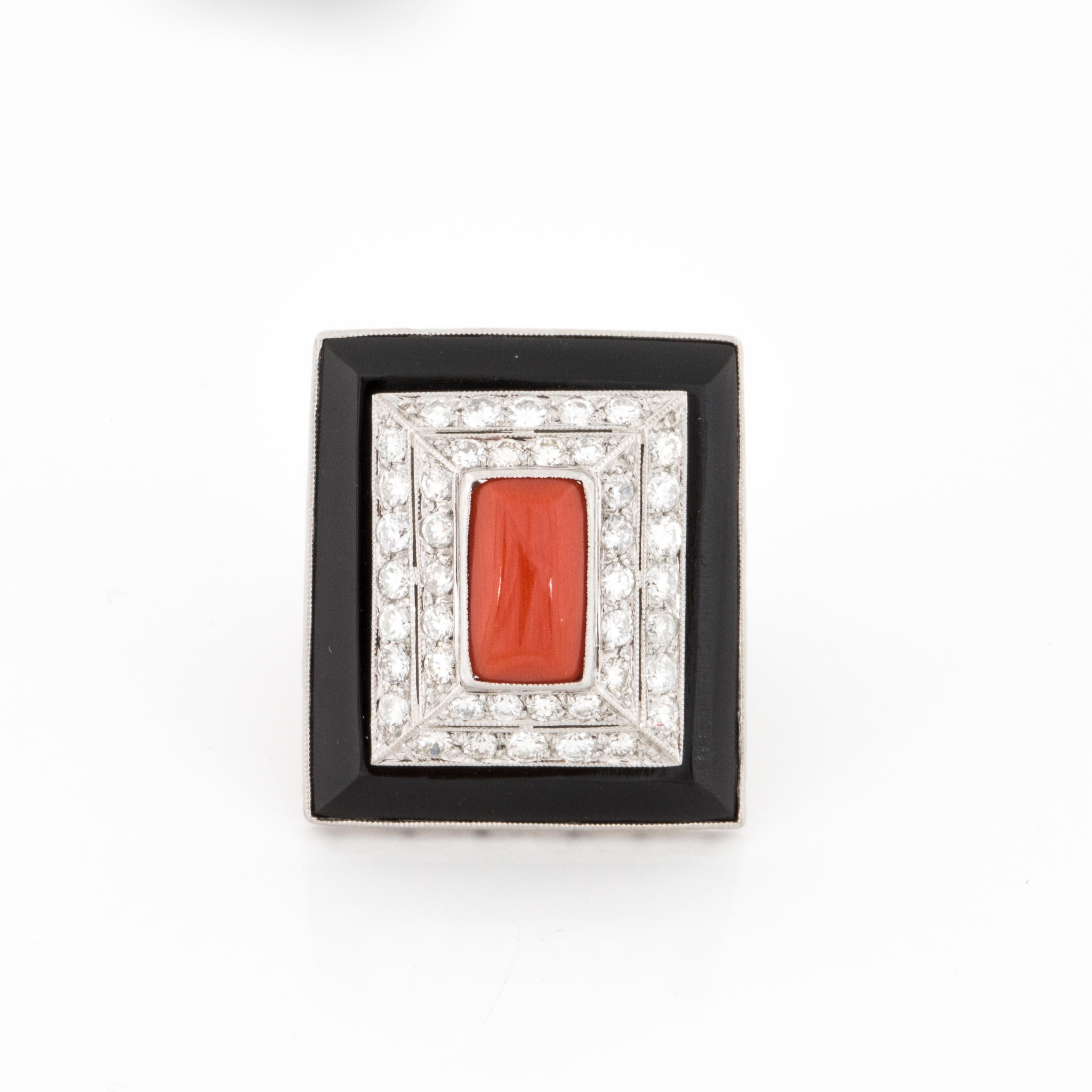 Deco inspired ring in platinum with onyx, diamonds and coral.  There is a cabochon elongated piece of coral in the center with a frame of diamonds and an onyx border.  There are 42 round diamonds that total 2.55 carats; G-I color and VS1-SI2