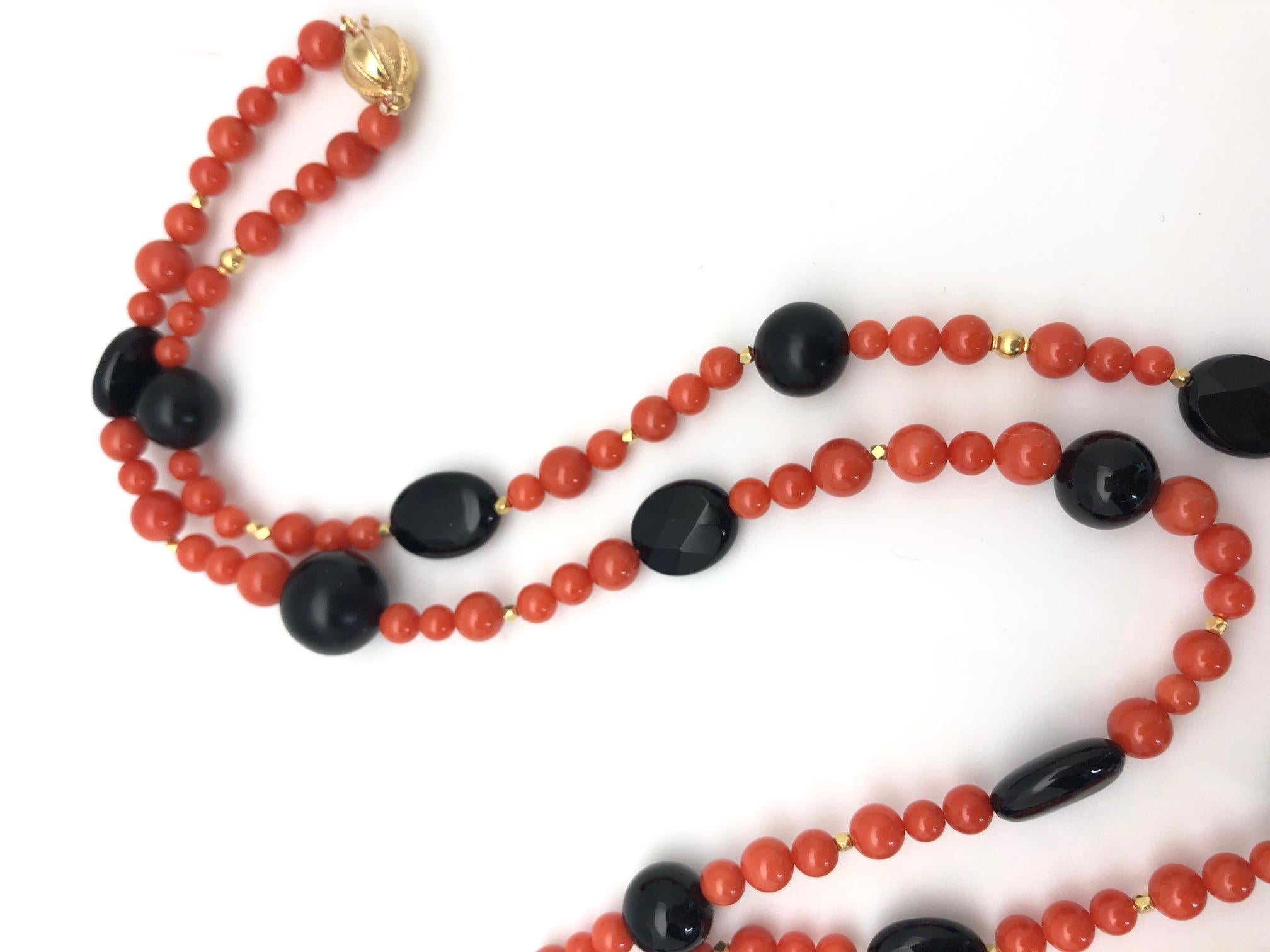 This elegant coral, onyx and gold beaded rope necklace offers both a dramatic color combination and a versatile length for endless possibilities. Round red coral beads in varying sizes are arranged with round and oval onyx beads in an eye-catching
