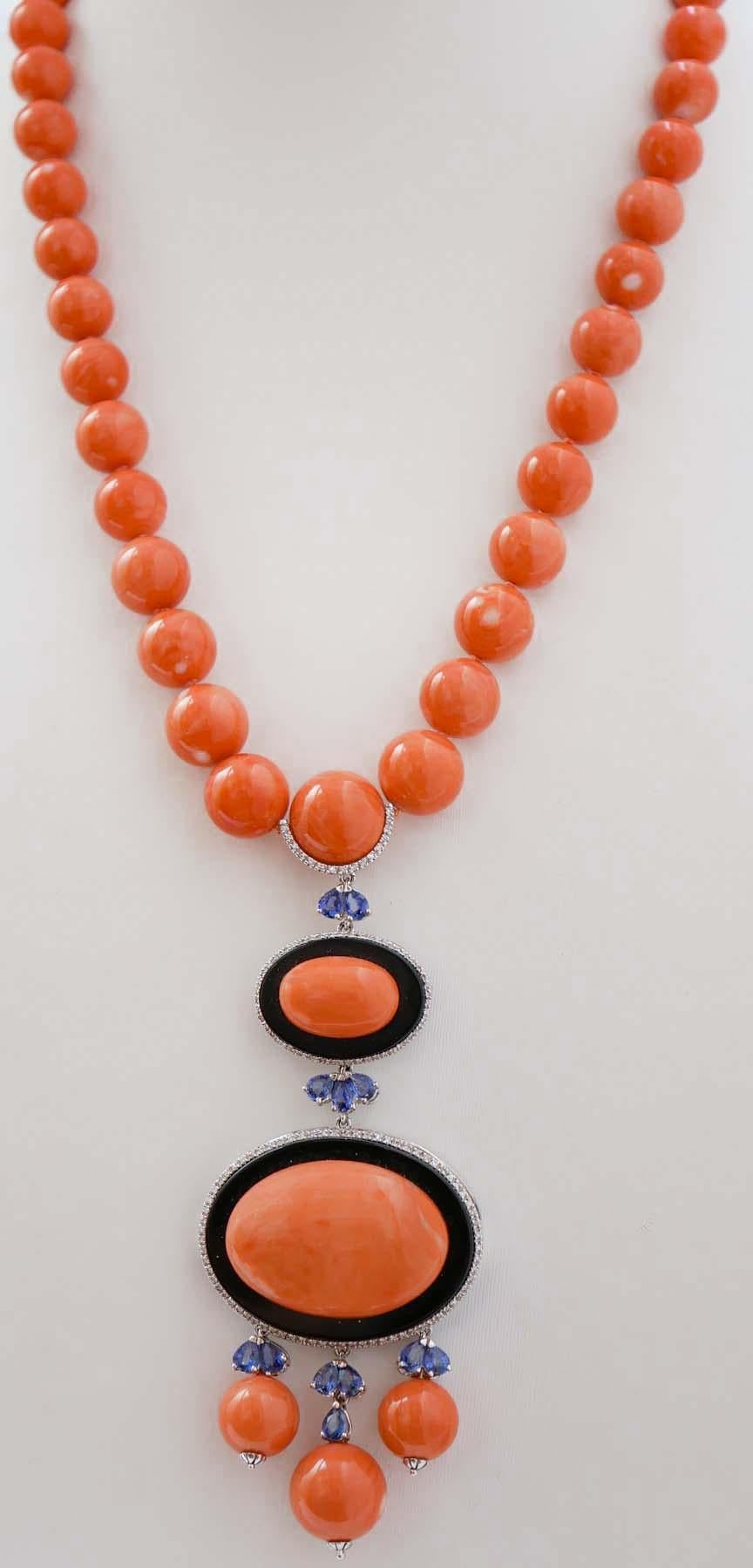Magnifica collana montata con un pendente in oro bianco 14 kt composto da corallo su onice circondato da diamanti. Il tutto circondato da una cornice di diamanti. Queste strutture sono collegate da zaffiri e, come pendenti, da zaffiri e sfere di