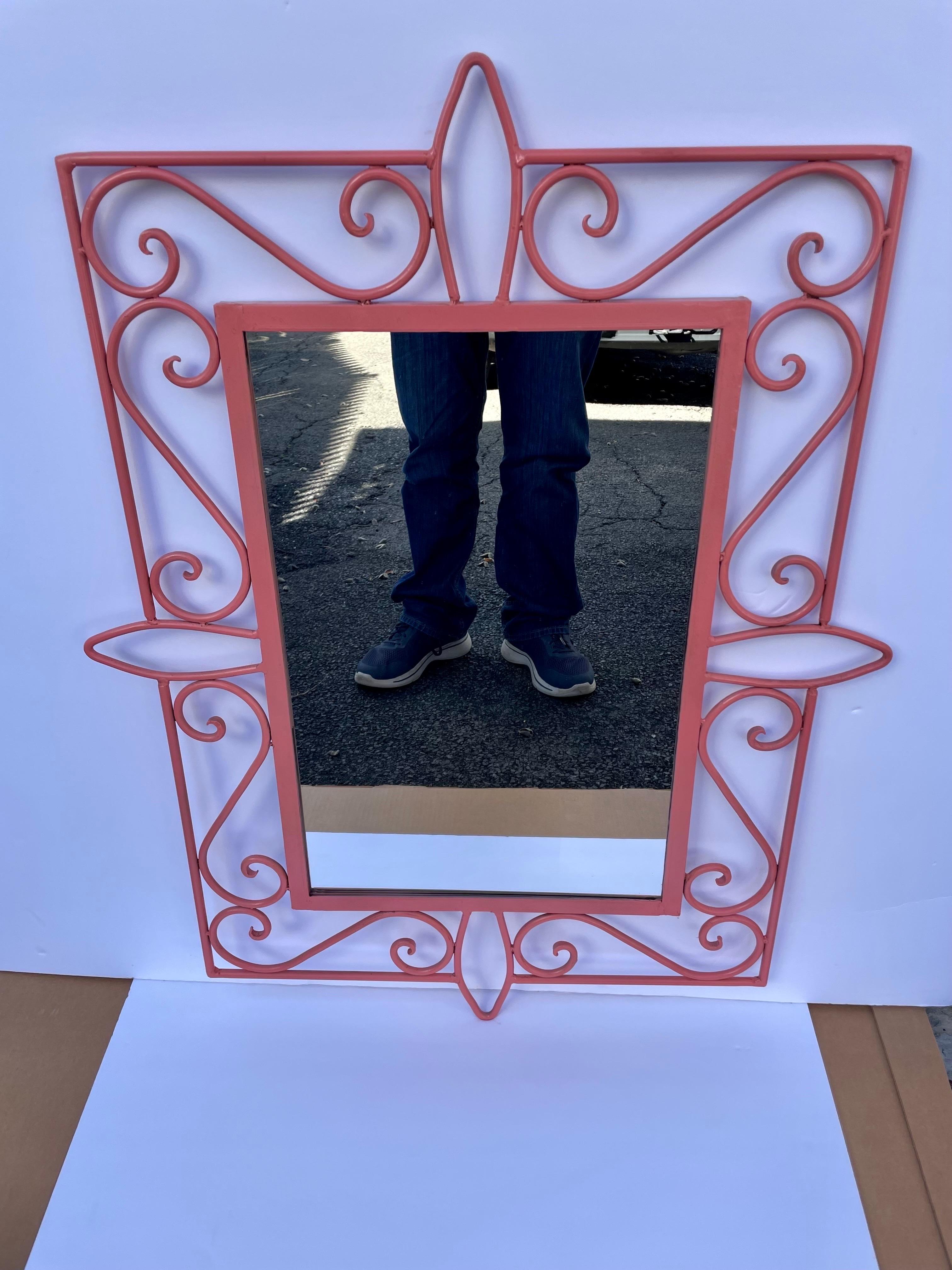 Coral painted curvy iron mirror. Repainted at some point. Nice detail to the curved pieces. Mirror has been replaced, measures 22