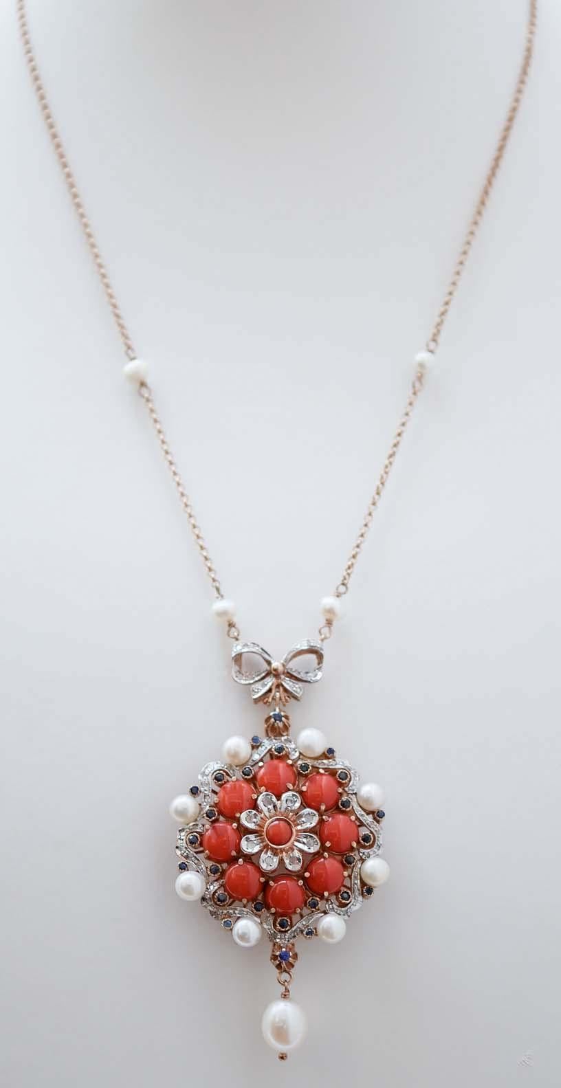 Retrò pendant necklace in 9 kt rose gold and silver structure mounted with a flower of diamonds and a central coral surrounded by corals, sapphires, and pearls. As pendant, a pearl. Along the chain, four pearls.
This necklace was totally handmade by