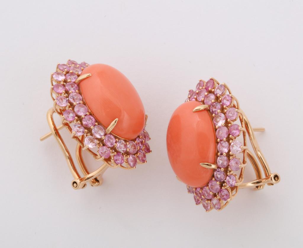 Perfectly matched pair of oval coral cabochons are mounted in a warm rose gold and surrounded by pink sapphires.  A subtle, and unique, touch is the use of various shades of pink sapphires.
Coral: app 14 1/2 carats
Pink sapphires: app. 5 1/4