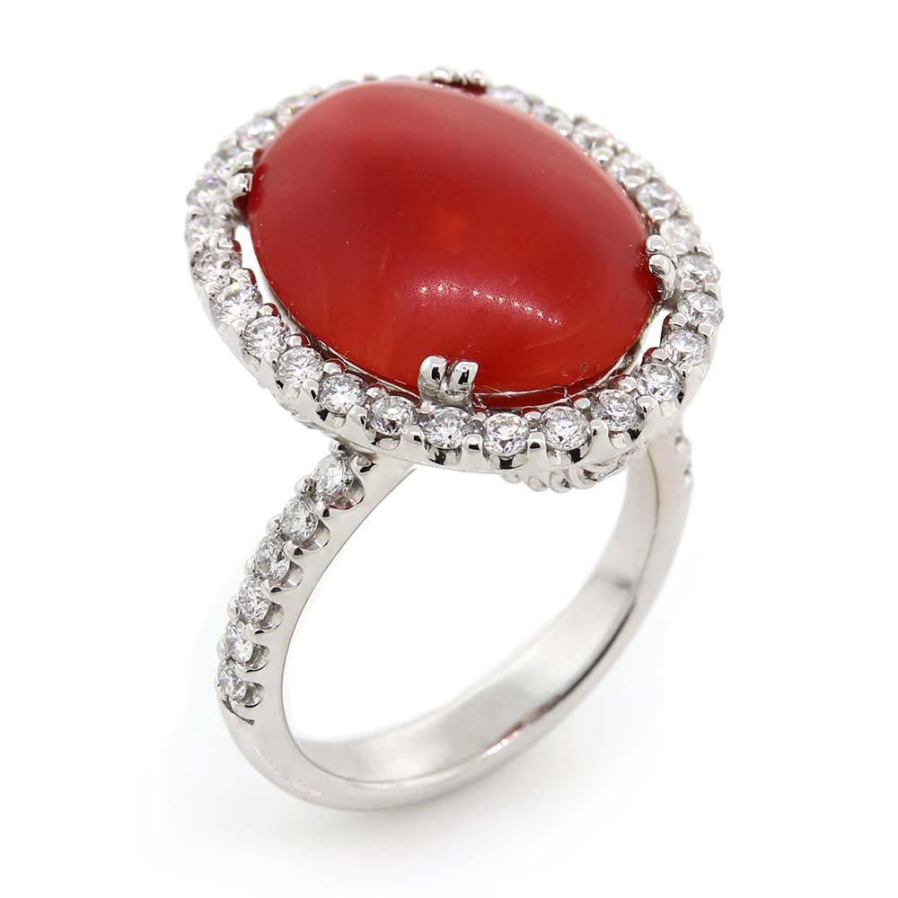 One cabochon coral of about 5.57 carats measuring 15.82×12.78×3.97 mm surrounded by 56 round brilliant cut diamonds of about 1.04 carats with a clarity of VS and color G. All stones are set in 18k white gold. The total weight of the ring is