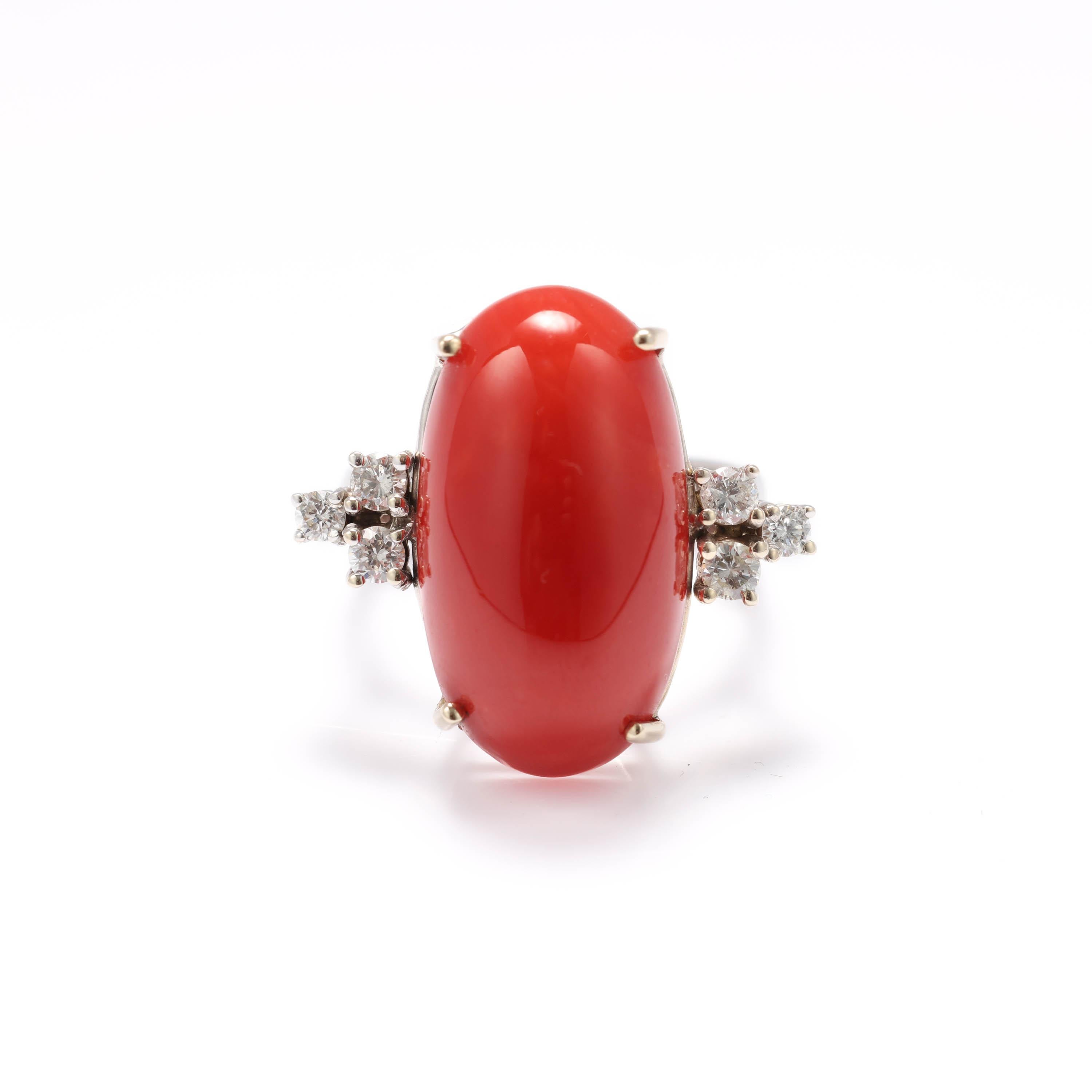 A gleaming lipstick red cabochon of natural precious coral is claw-set into a hand-fabricated 18K white gold mounting in this midcentury ring. Three eye-clean and near-colorless diamonds are set on either side like parenthesis and weigh around .35
