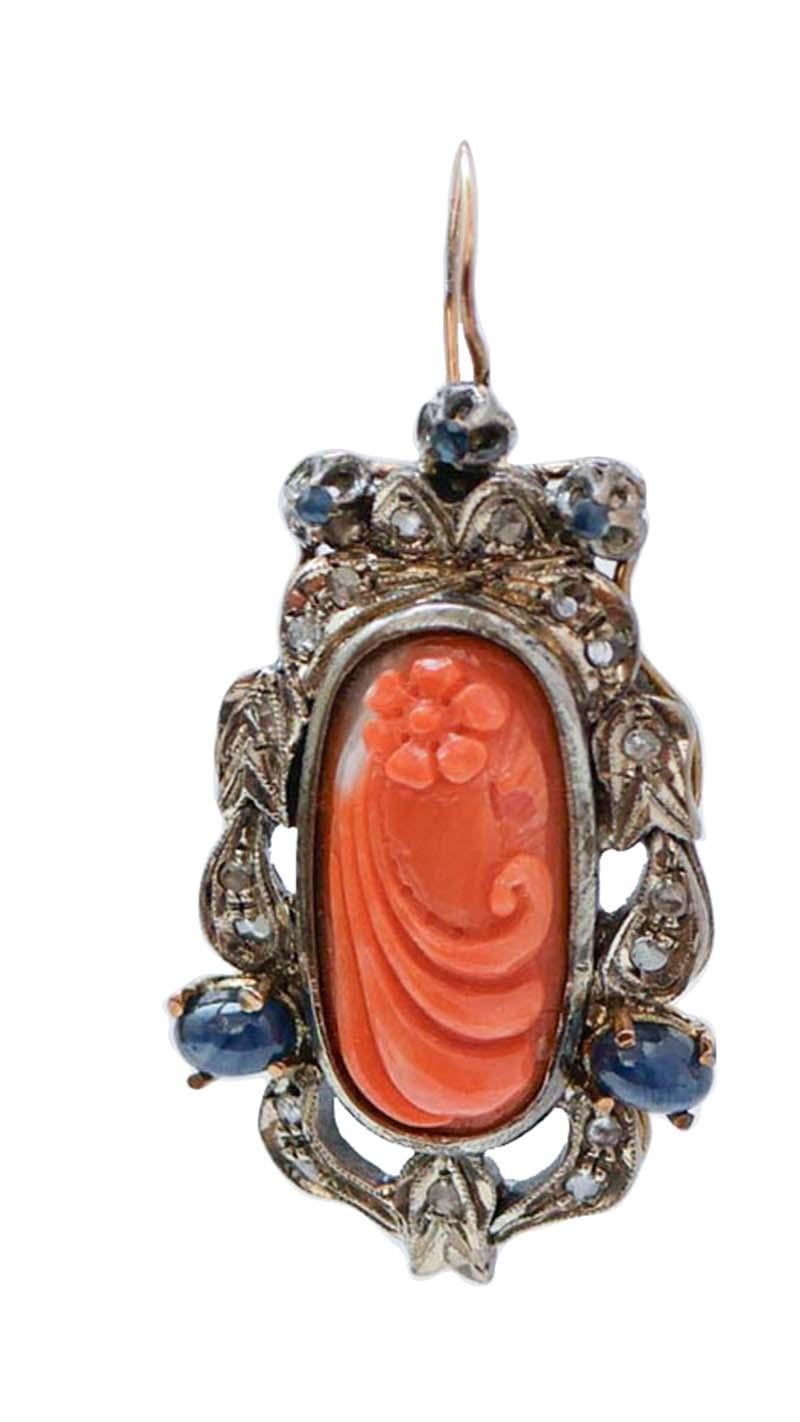 Orecchini Retrò in oro rosa 14 kt e struttura in argento montata con un corallo intagliato centrale circondato da una cornice di diamanti e zaffiri.
Questi orecchini sono stati realizzati totalmente a mano da maestri orafi italiani e sono in
