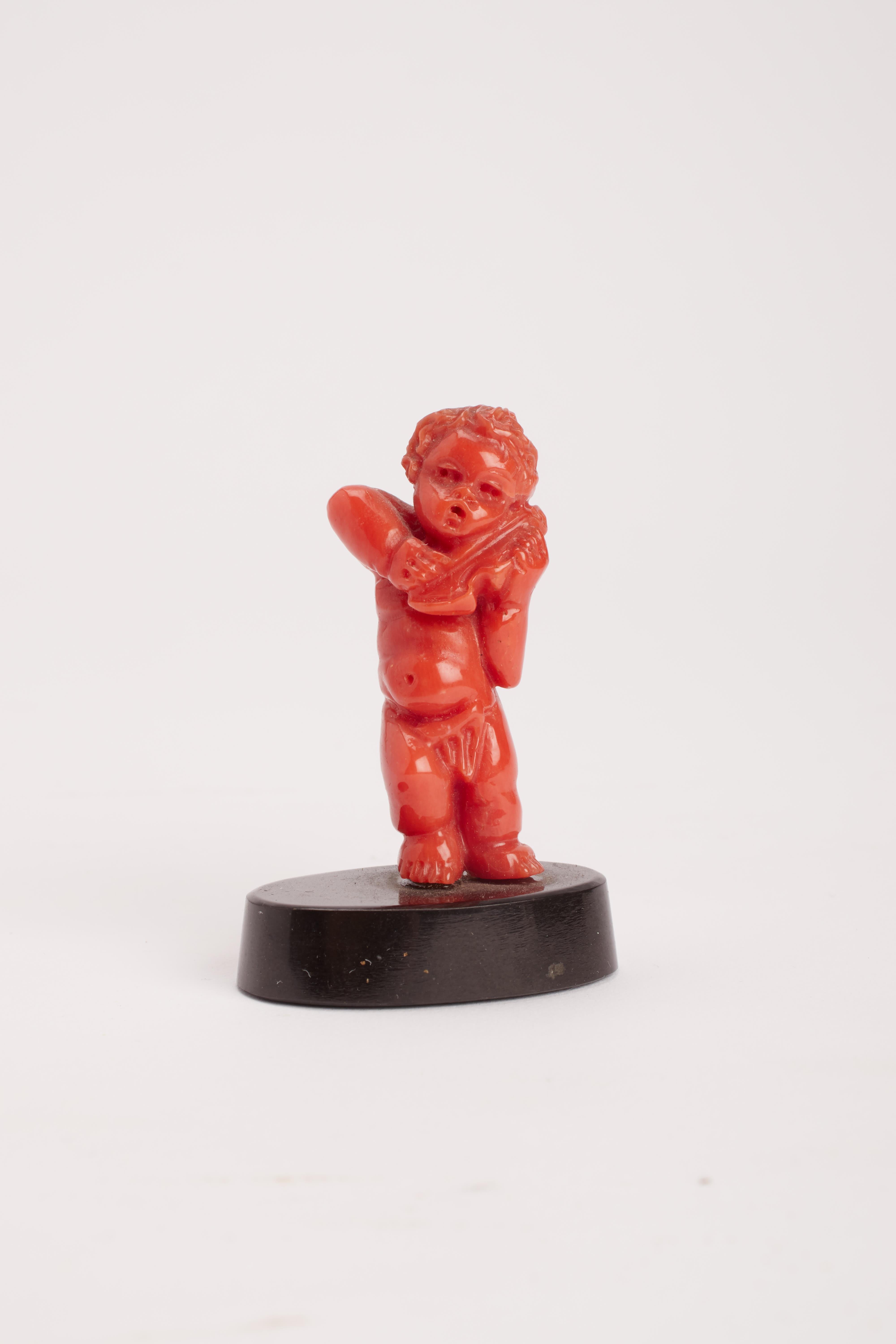 Grand Tour sculpture depicting a little putto playing a violin, made out of Mediterranean sea red coral. Black onyx base. Neaples, Italy 1860 ca.