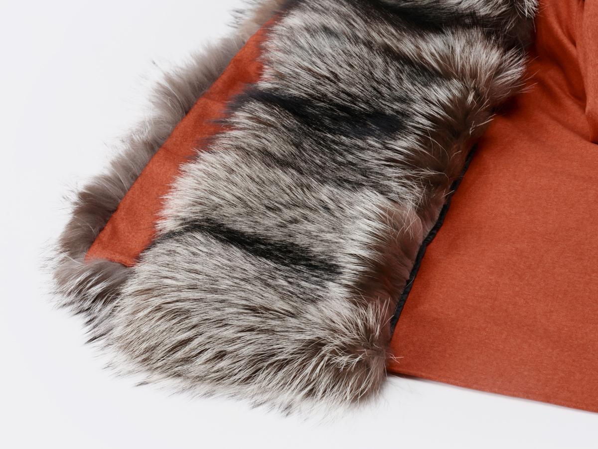 This is a design piece that has to stand out.

The coral-coloured cashmere and silk blanket are contrasted by the natural grey-black hue of the silver fox fur, hemmed on the short sides of the plaid.

In order to compensate for the lightness of the