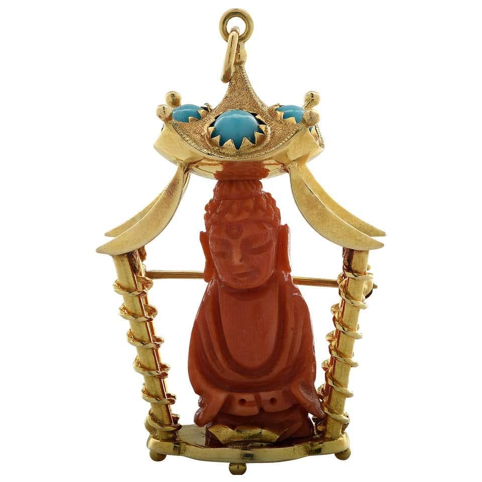 
A beautiful 18 karat yellow gold brooch-pendant centering a carved coral Buddha seated in a pagoda, embellished with natural turquoise.