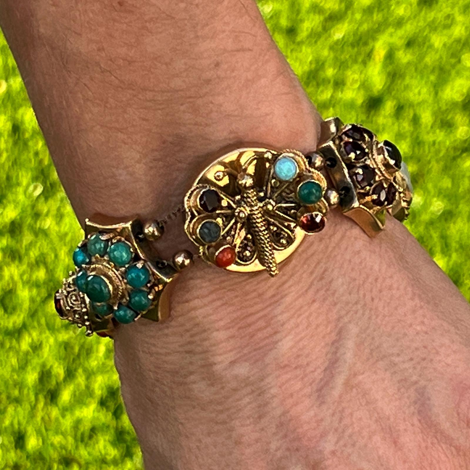 Fabulous original slide bracelet crafted in 14 karat yellow gold. The bracelet features a center butterfly slide, cameo, and tigers eye, coral, and turquoise gemstones. The slide measures 7.5 inches in length, 15-25mm in width, box clasp, and chain