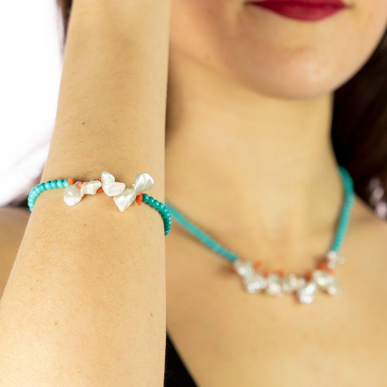 Un delicato filo di perline turchesi con bracciale e collana centrale in madreperla e scaglie di corallo. Immergiti nella bellezza di questo set dal design unico con pietre naturali piene di vita e di colore. Un gioiello d'ispirazione hawaiana che