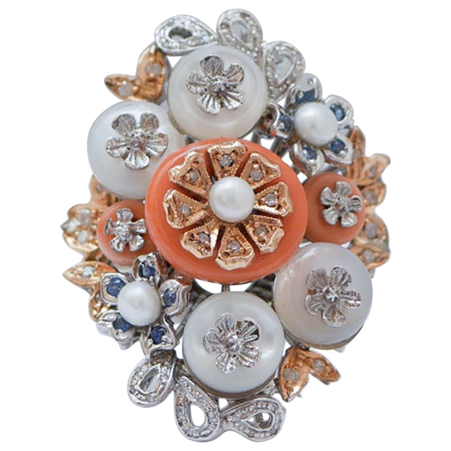 Anello in corallo, pietre bianche, perle, diamanti, zaffiri, oro bianco e rosa 14Kt.