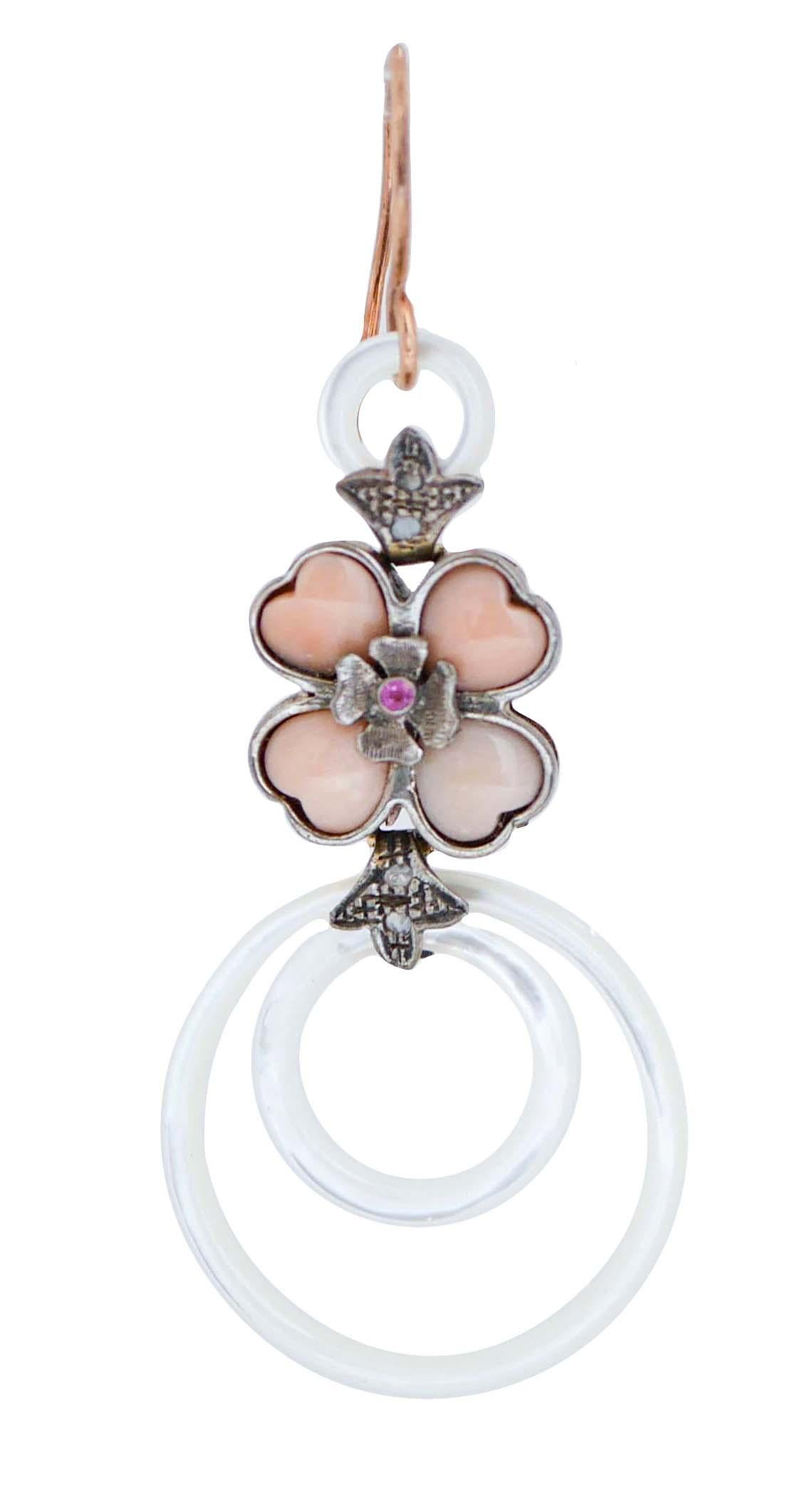 Beautiful dangle earrings in 9 kt rose gold and silver structure mounted with an hoop of white stone in the upper part; in the middle, a structure with diamonds, coral and ruby. As pendant, two hoop of white stone.
These earrings were totally
