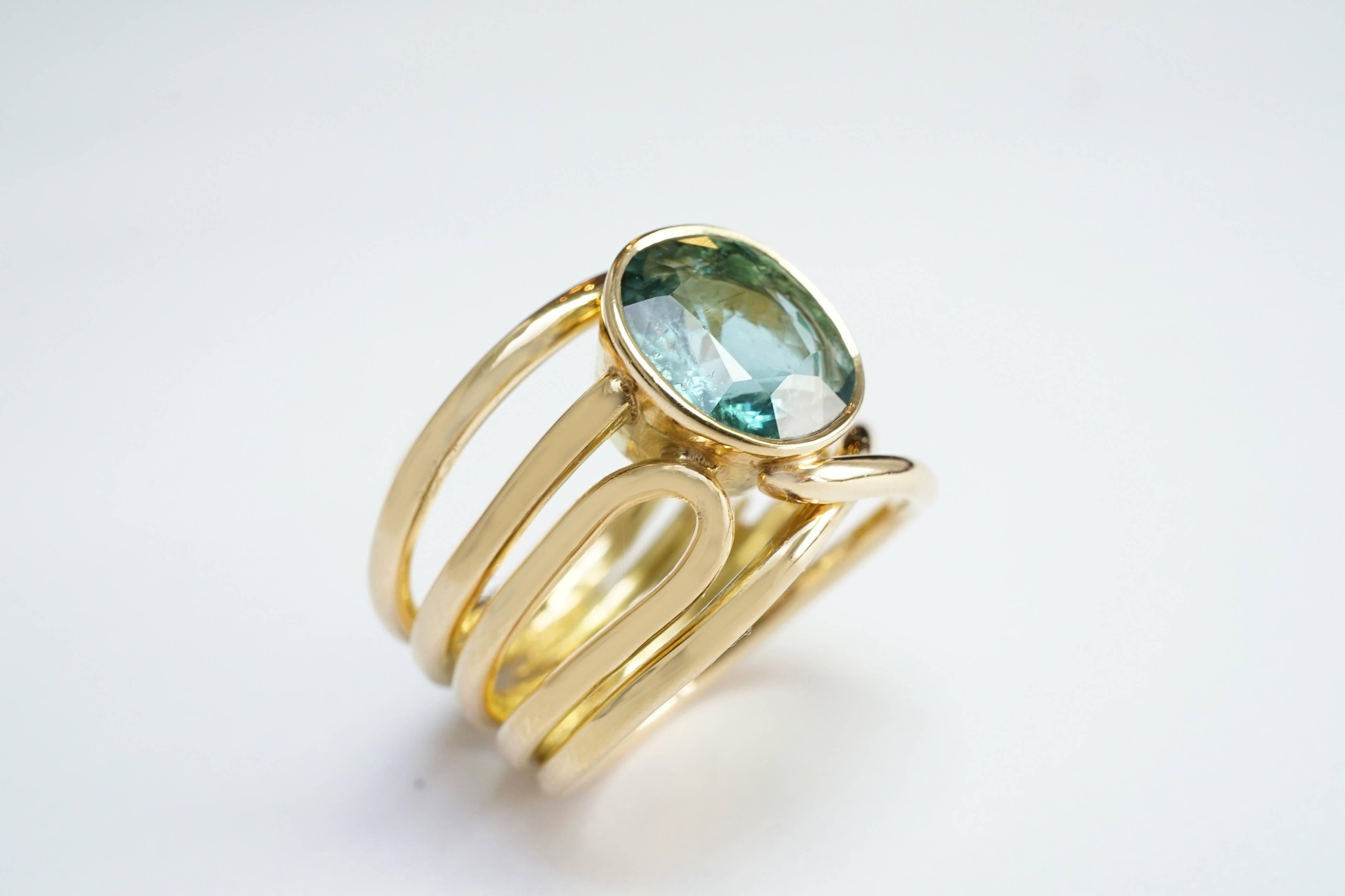 Coralie Van Caloen Gold 18 Carat Band Ring With Turquoise Tourmaline is entirely hand made and forged in Belgium by experts goldsmiths therefore it is a 
very unique piece. The fluidity of cords give the ring a feminine, contemporary and elegant