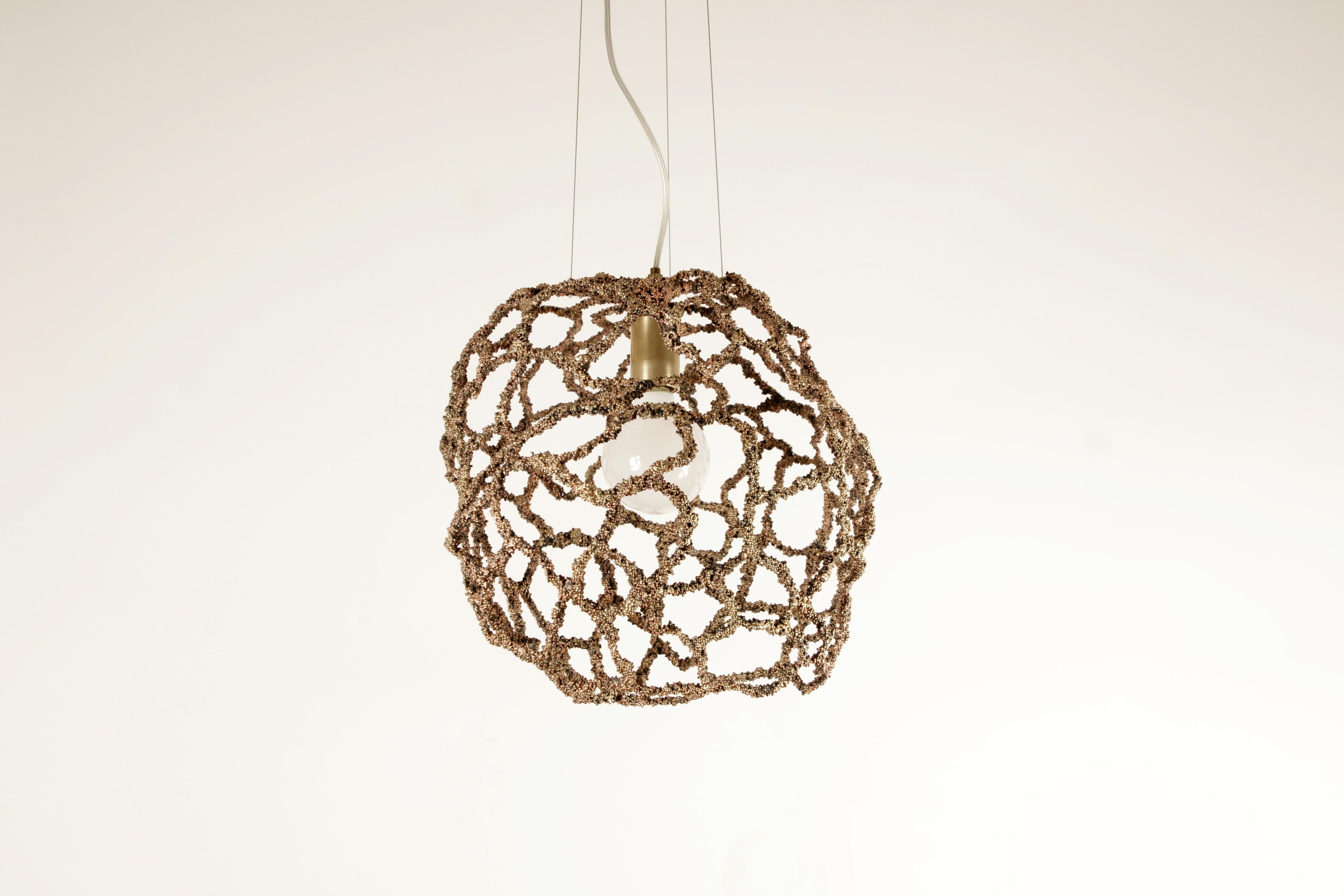 Core pendant light by Johannes Hemann
Material: Steel, brass
Dimensions: Ø 35 x H 48 cm

Just like the universe is made from smallest parts, the atoms, Core has been built from small beads. It is an experiment to see how small parts can built a