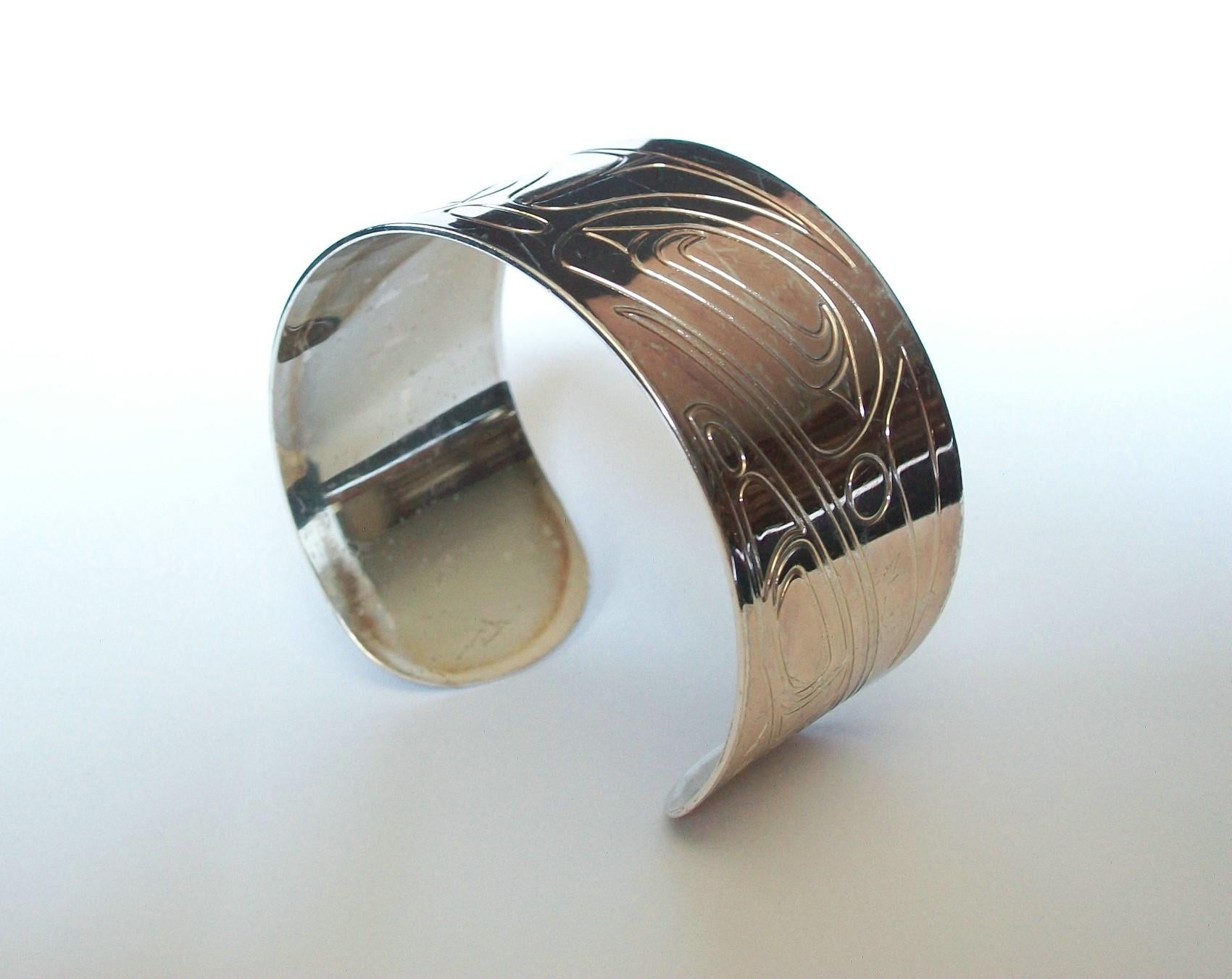 COREY W. MORAES (Designer) - Tsimshian - Canadian Aboriginal white metal cuff bracelet - stamped raven design to the entire band face - fits a small wrist - signed on the back of the band - online retailers mark - Canada (Pacific Northwest) - circa