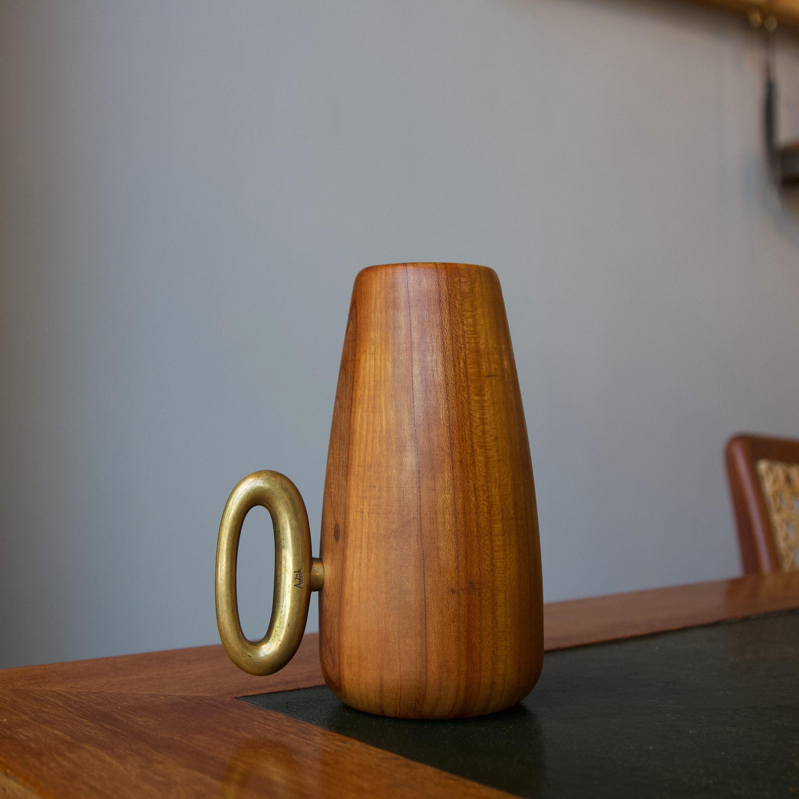 The brass handle of this turned walnut cup made by Carl Auböck II, C.1949, deceptively conceals one of the many functions of this delightfully tactile object. The cup itself can be used to store a multitude of dinner table essentials such as wooden
