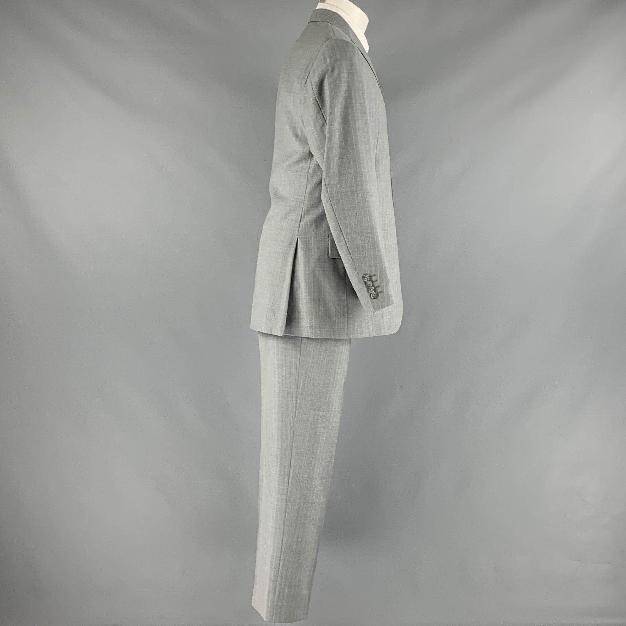 CORNELIANI suit in a grey and cream pinstripe wool with a full liner and includes a single breasted, three button sport coat with notch lapel and matching flat front trousers.Very Good Pre-Owned Condition. Marks on trousers. 

Marked:   40