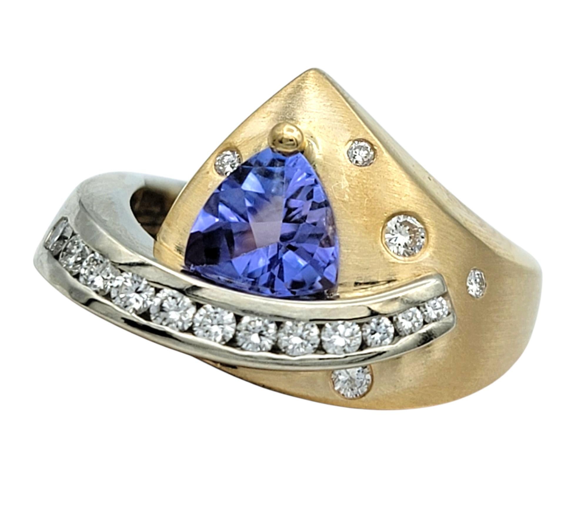 Ring Size: 7.5

This bold and architectural ring by Cornelis Hollander is crafted in a striking combination of 14 karat yellow and white gold. At the center is a triangle-cut buff top tanzanite, displaying a grayish violet hue. The geometric design