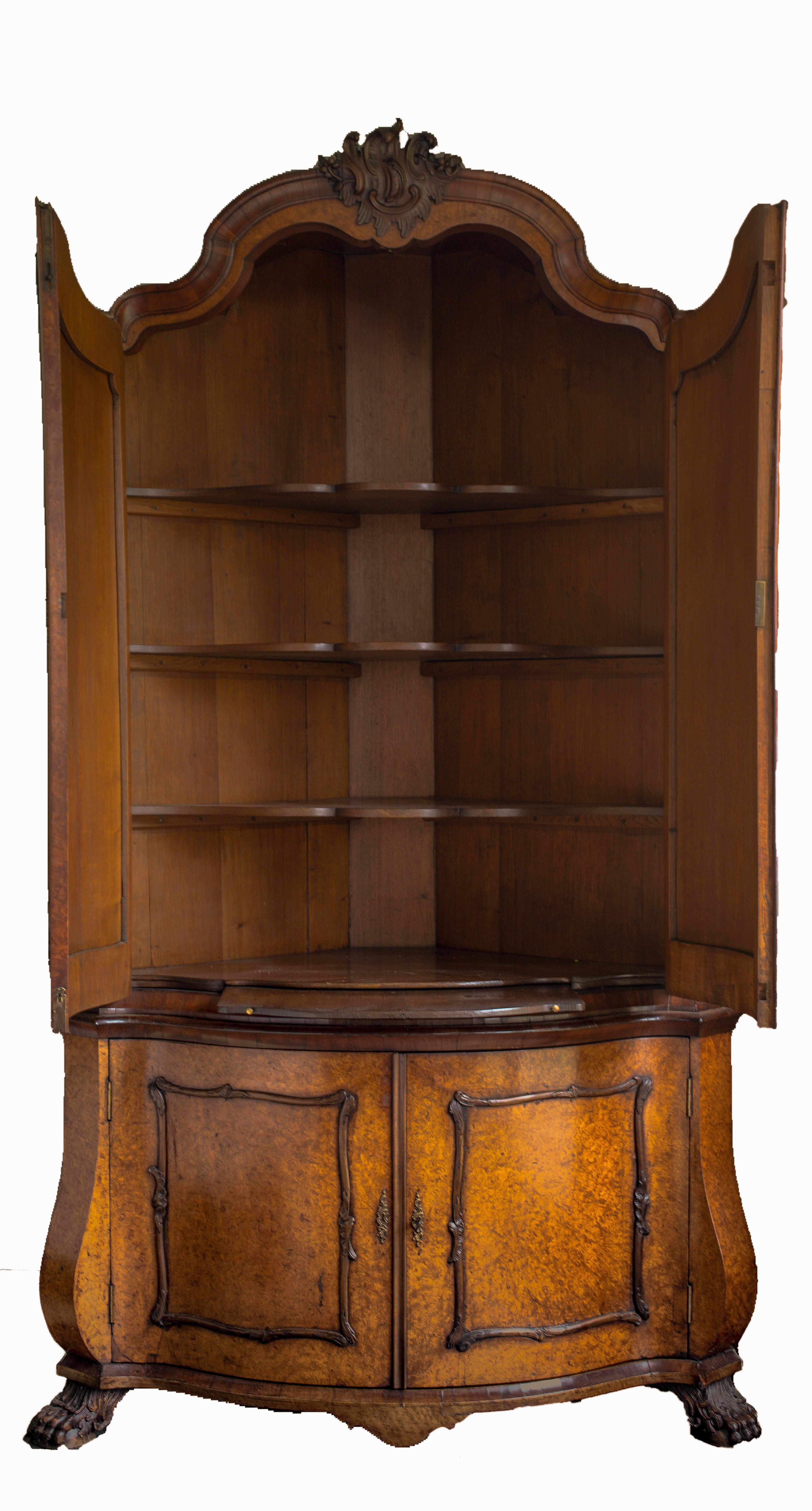 A Dutch Rococo amboyna burl, walnut-burr and walnut veneer bow-fronted corner buffet cabinet, third quarter 18th century.
The arched moulded corniche decorated with four carved C-scrolls with rockwork and flower-heads.
Above a pair of arched