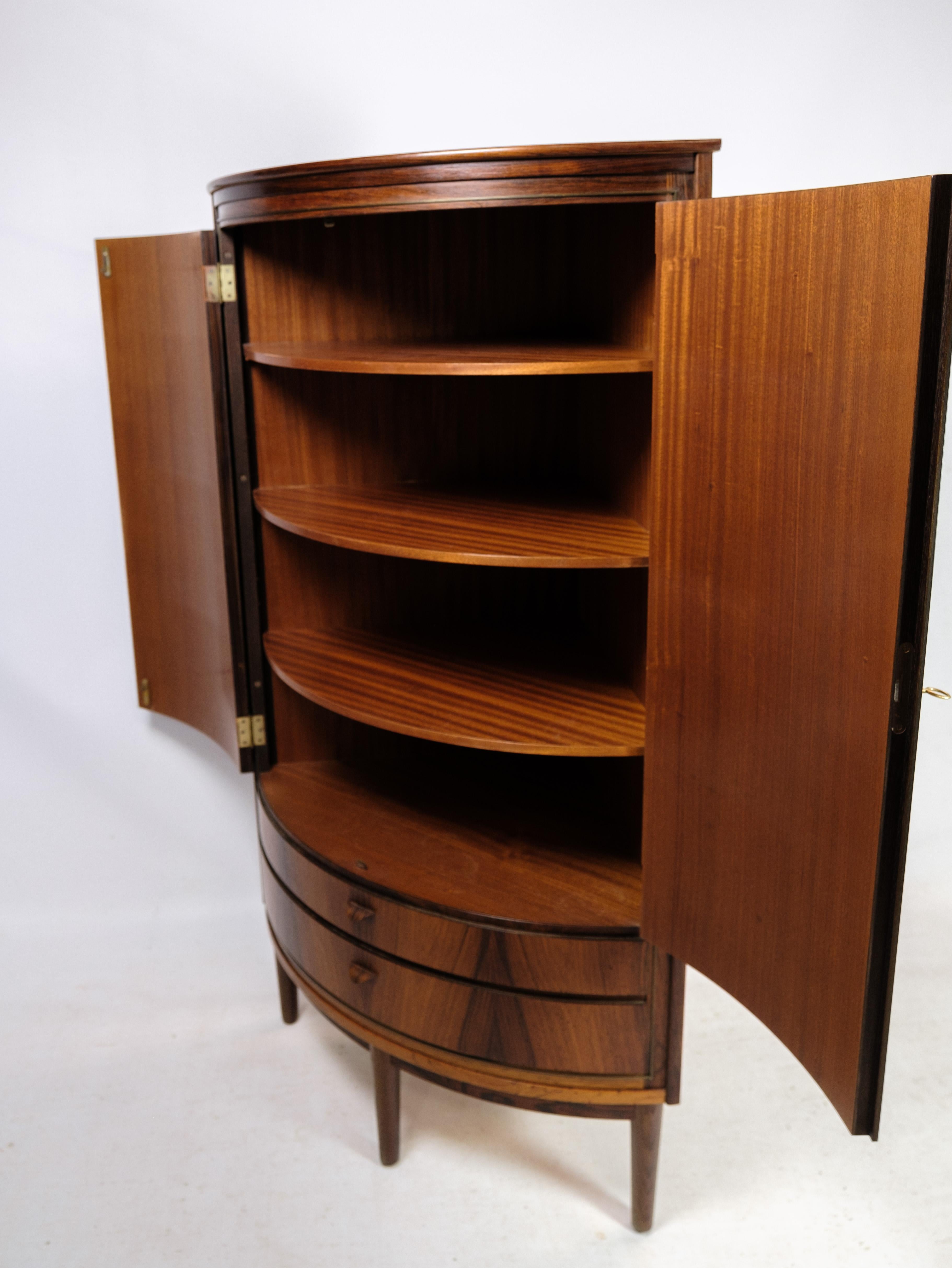 Corner cabinet in rosewood of Danish design from around the 1960s. The corner cabinet has 2 drawers at the bottom, as well as 2 doors with three shelves inside the cabinet. The cabinet has 4 legs in total, which are visible from the front. It is a