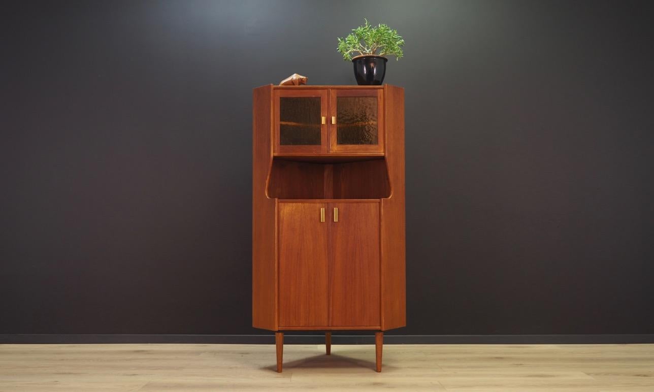 A fantastic 1960s-1970s corner cabinet. Danish design, Minimalist form. The surface of the furniture finished with teak veneer, glass doors. Three shelves in the interior. Maintained in good condition (minor bruises and scratches, filled veneer
