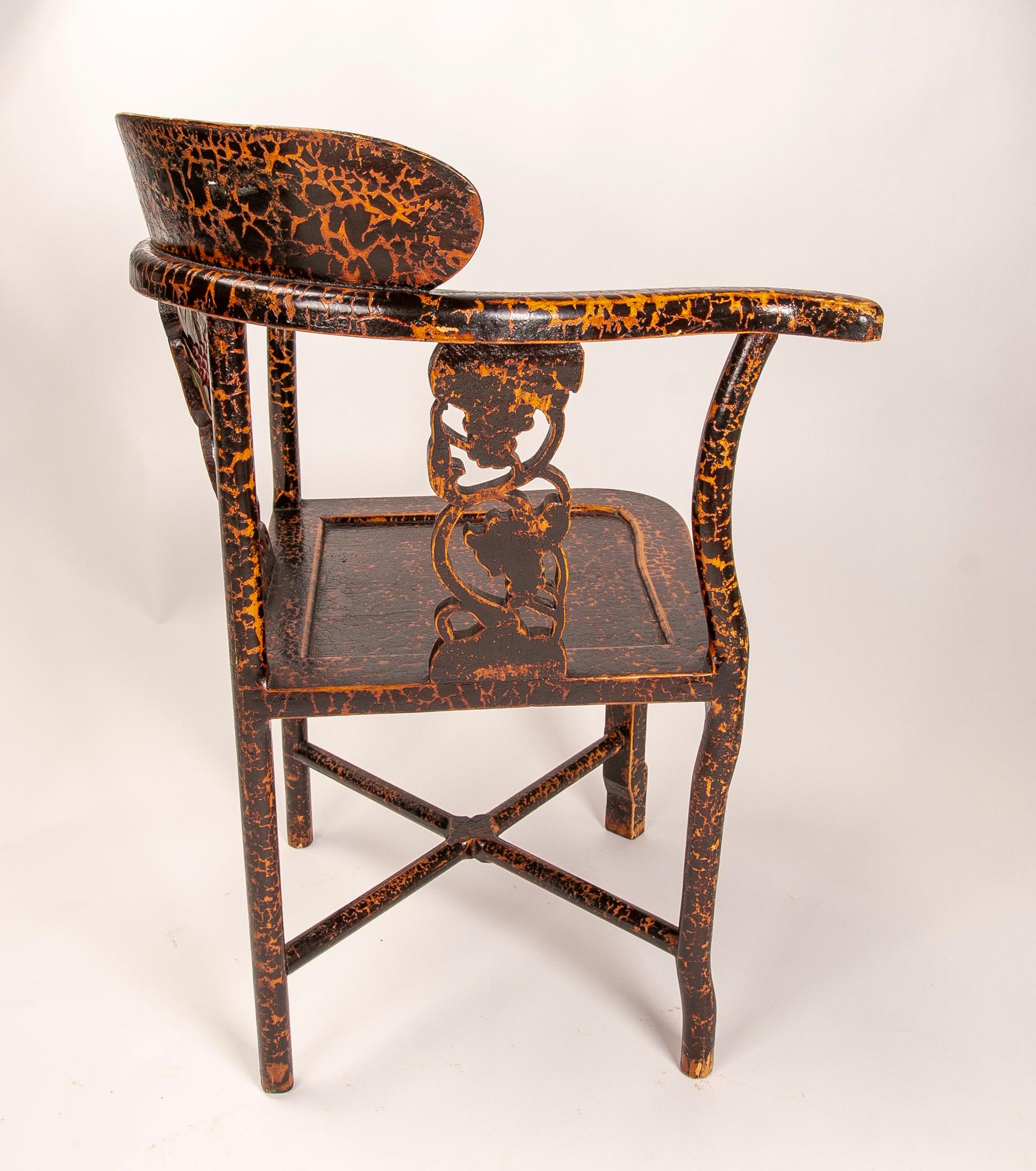 Corner chair with lacquered wooden arms and carved flowers on the backrest.
