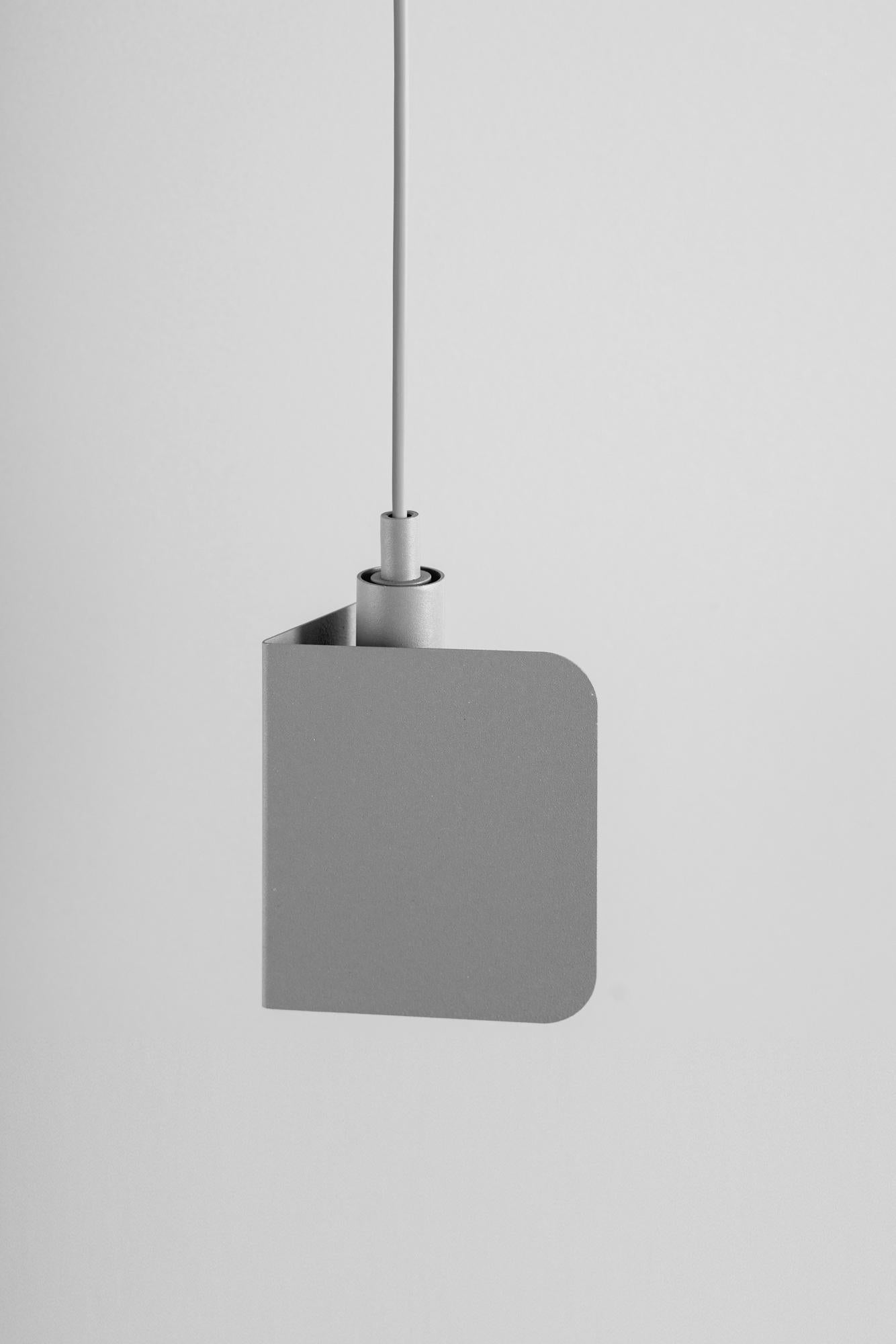Lampada a sospensione angolare piccola grigia di +kouple
Dimensioni: D. 10,5 x L. 13,5 x H. 19 cm. 
Materiali: Acciaio verniciato a polvere.

Disponibile in diverse opzioni di colore. Disponibile in due diverse dimensioni. La lunghezza del cavo in