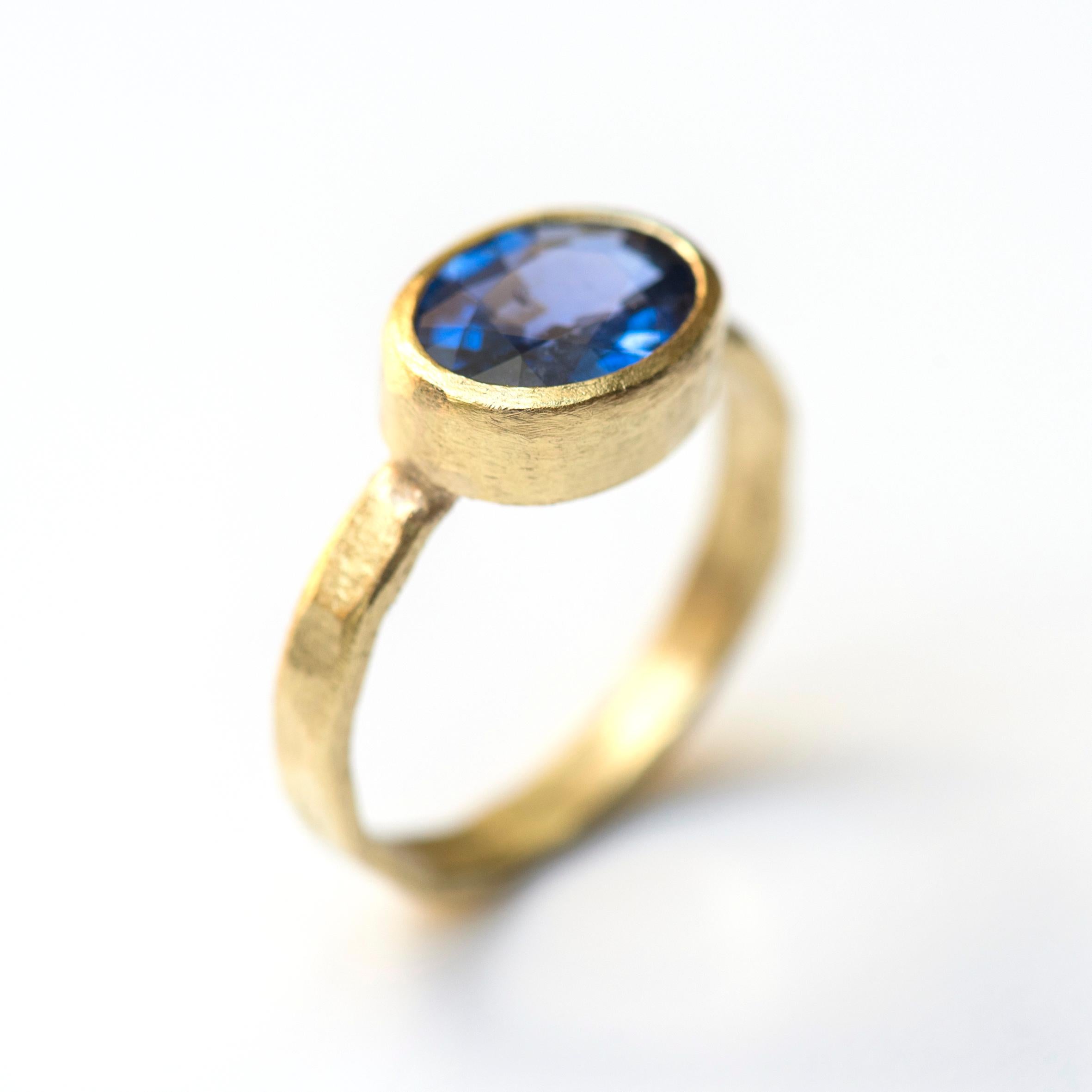 A stunning cornflower blue sapphire set in 18k yellow gold with a hammered texture finish handmade by Disa Allsopp.

The hammered texture band is 3mm wide while the stone sits at 4mm height. The contrast between the warm 18k gold and blue of the