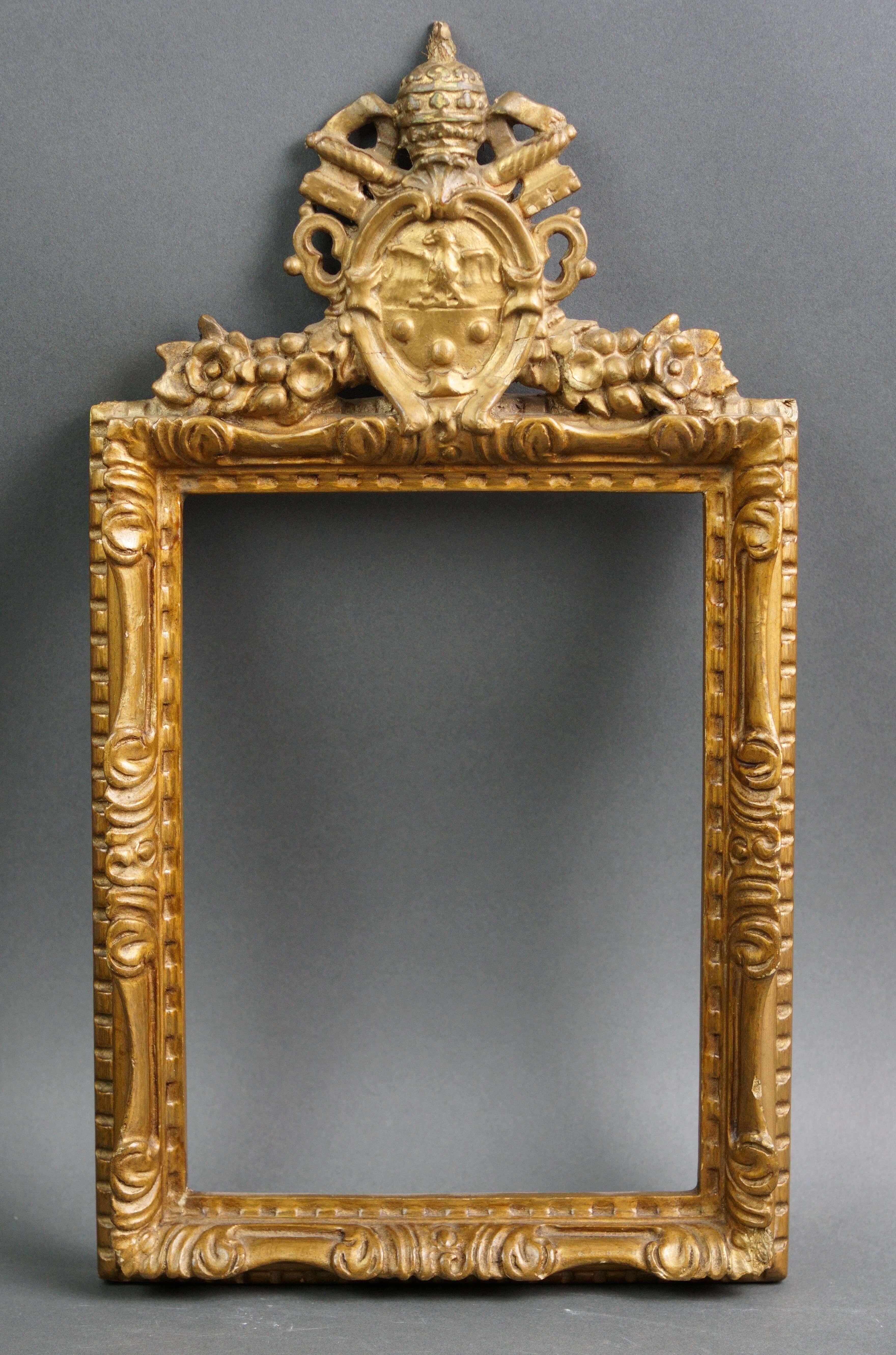 Rara cornice italiana del XVIII secolo in legno scolpito e dorato sovrastata da uno stemma recante gli attributi papali della mitra e delle chiavi incrociate.   

Misure 
H max cm 41 
L max cm 23,5 
Luce cm 23 x 17 
Int cm 25,5 x 19,5