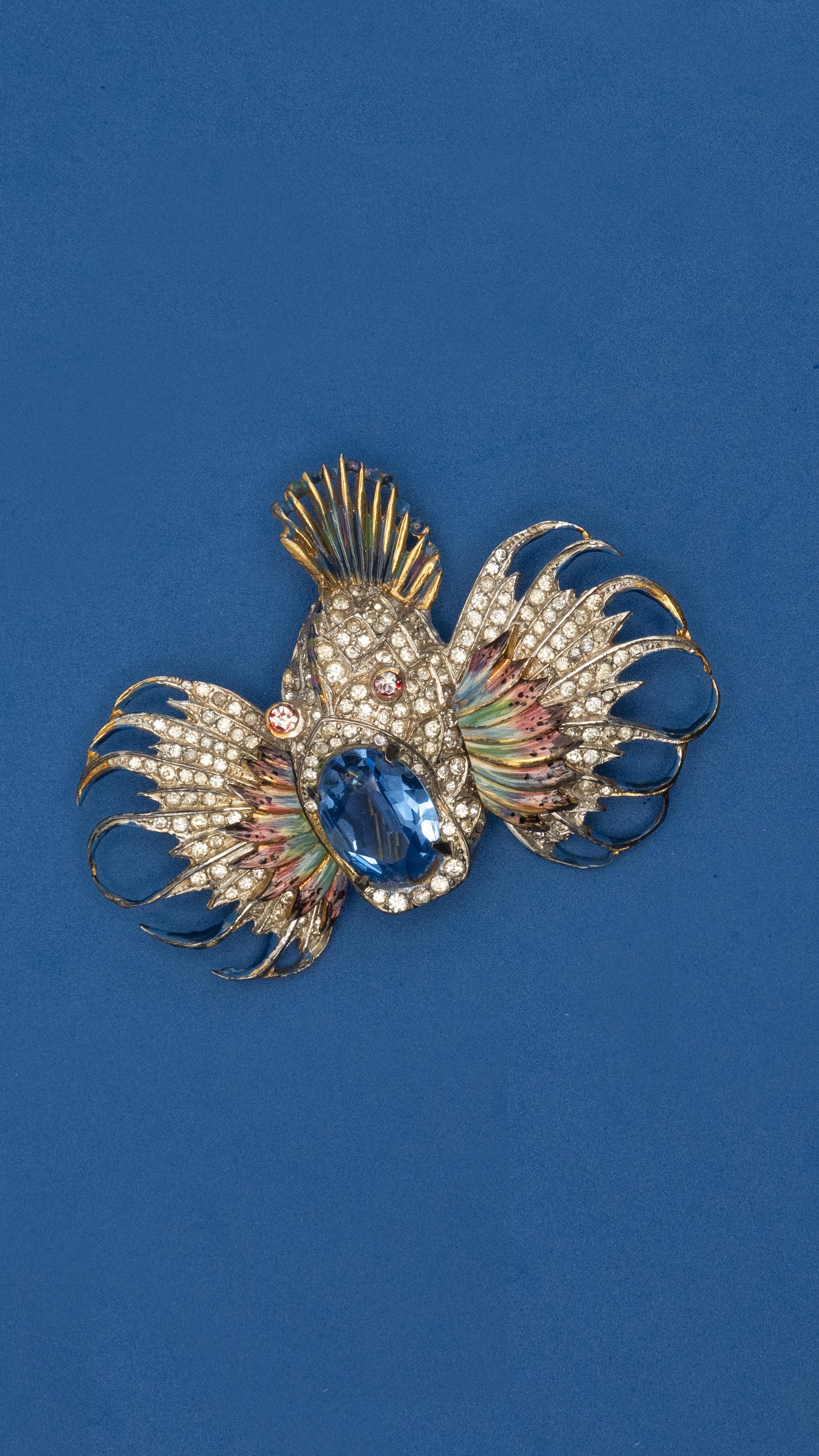 1944 Coro Craft sterling enamel rock fish brooch designed by Adolph Katz, set with a blue crystal glass as the mouth

Approximate Weight: 46.3 grams

Approximate Measurement: 3” x 2.15”
Blue crystal glass - 18mm x 12.8mm

Hallmark: CORO CRAFT